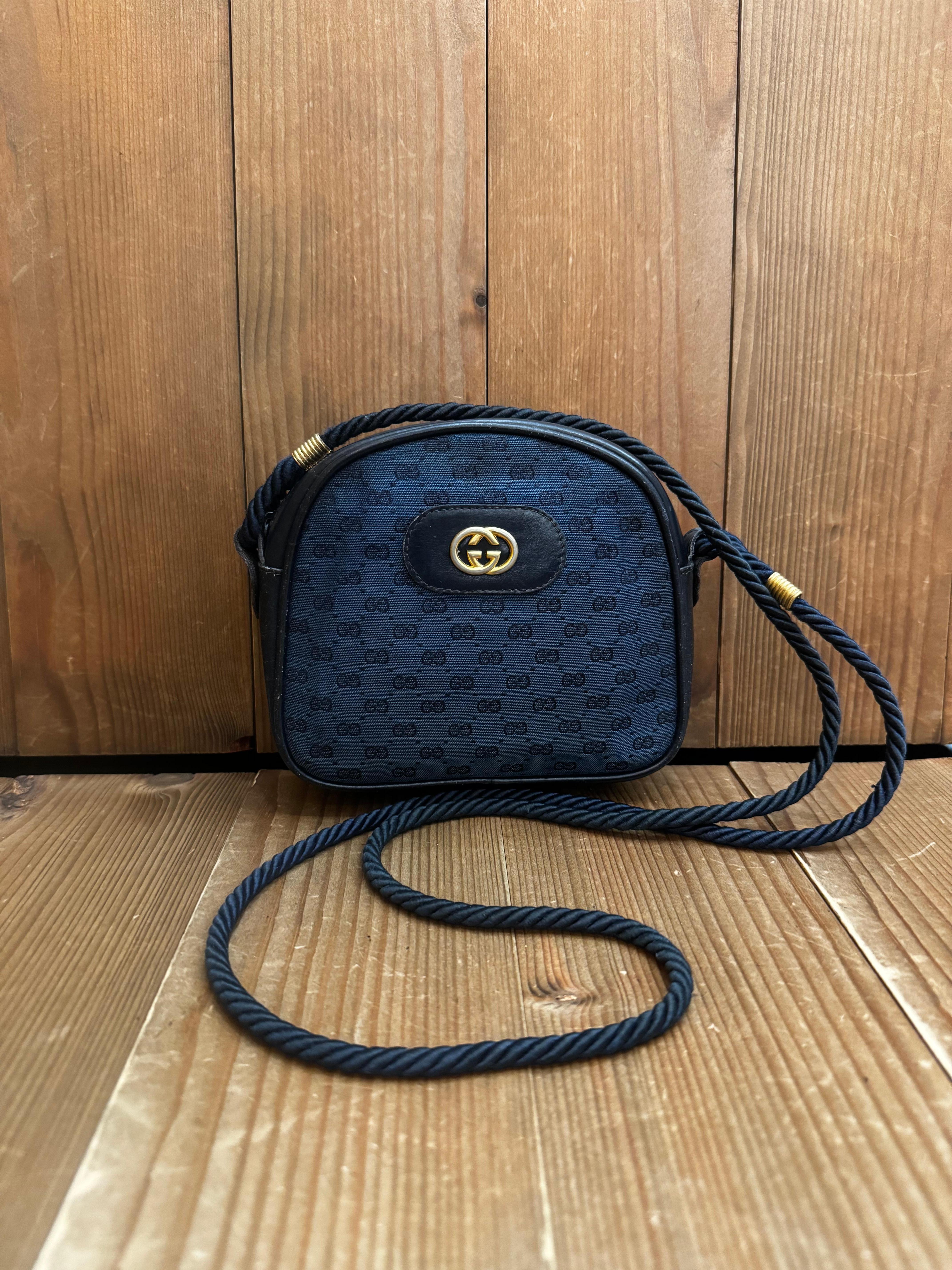 This vintage GUCCI micro crossbody bag is crafted of micro CC jacquard in navy featuring gold toned hardware and a rope strap. Top zipper closure opens to a leather interior in black. Made in Italy. Measures approximately 5.75 x 5 x 1.5 inches Strap