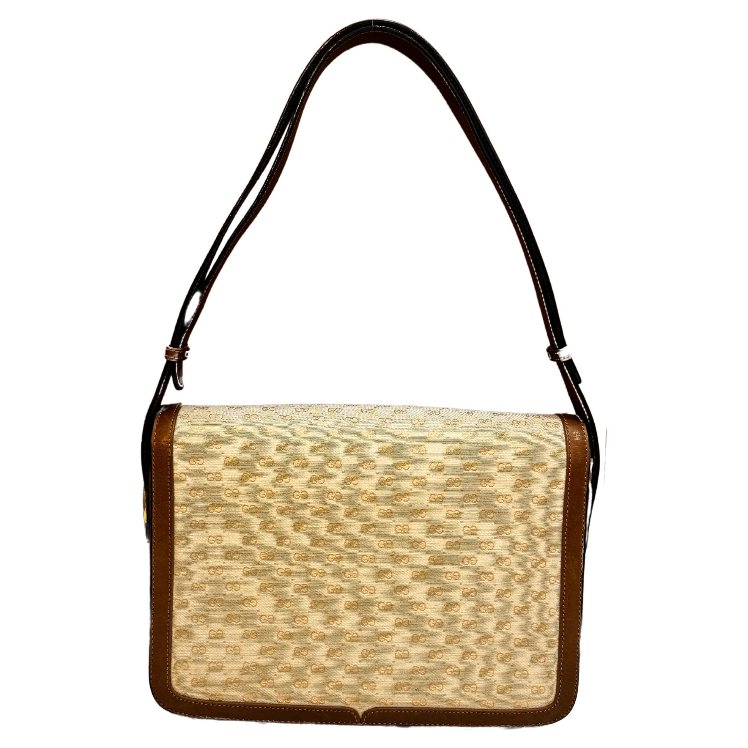 This Vintage GUCCI shoulder bag is crafted of micro GG jacquard in off-white trimmed with smooth brown calfskin leather featuring gold and silver toned hardware. Front buckle closure opens to two main compartments lined with brown leather featuring