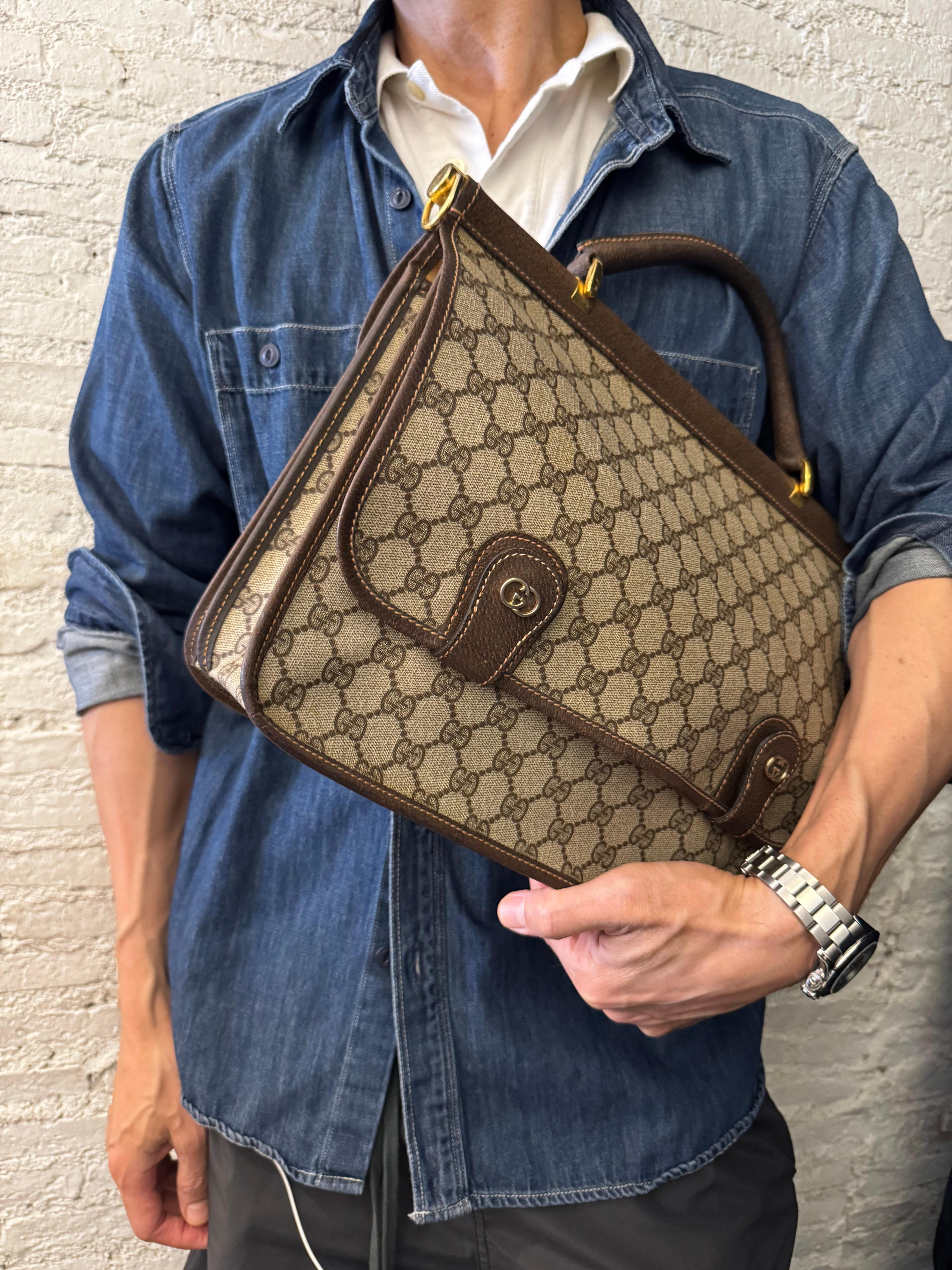 This vintage GUCCI briefcase business bag is crafted of brown GG coated canvas and pigskin leather. One side double magnetic snap flap closure opens to an unlined interior with a zippered pocket. The other side flap with push-lock closure opens to