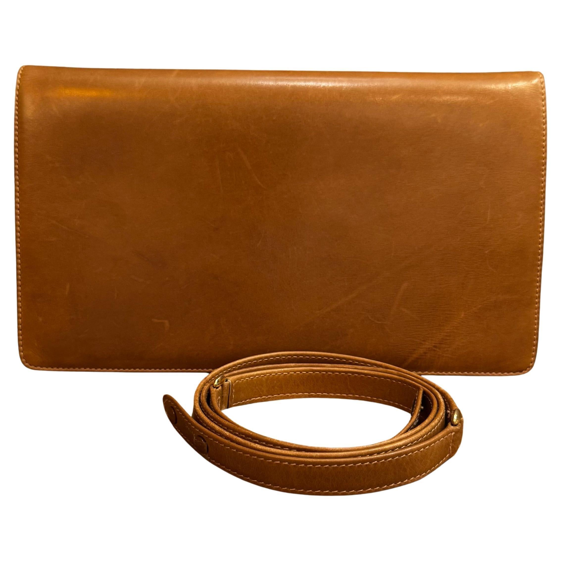 This vintage GUCCI 2-way clutch shoulder bag is crafted of smooth cowhide leather in brown featuring GG horsebit on the front. Front flap snap closure opens to a black leather interior with a zippered pocket. The vintage piece can be carried as a