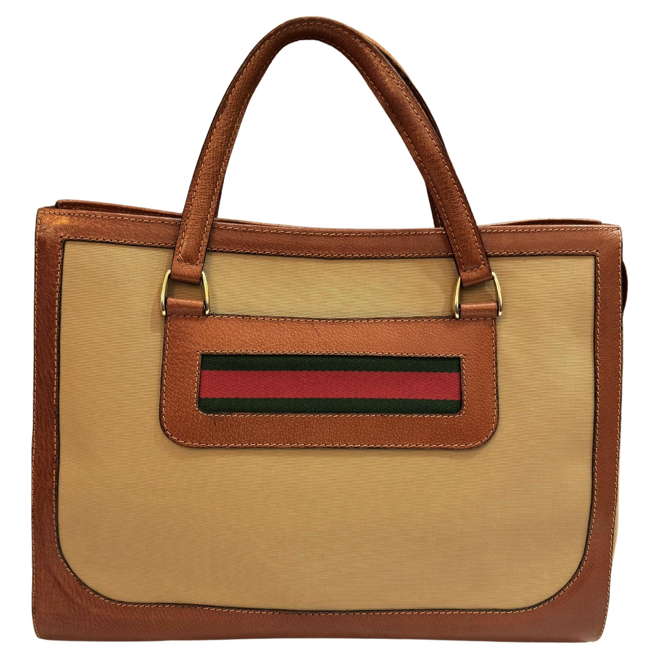 This vintage Gucci book tote is crafted of khaki canvas and brown pigskin leather decorated with an iconic Gucci’s red/green band. Made in Italy. Measures approximately 15.75 x 13 x 5.5 inches Handle drop 5 inches.

Condition - Fair vintage