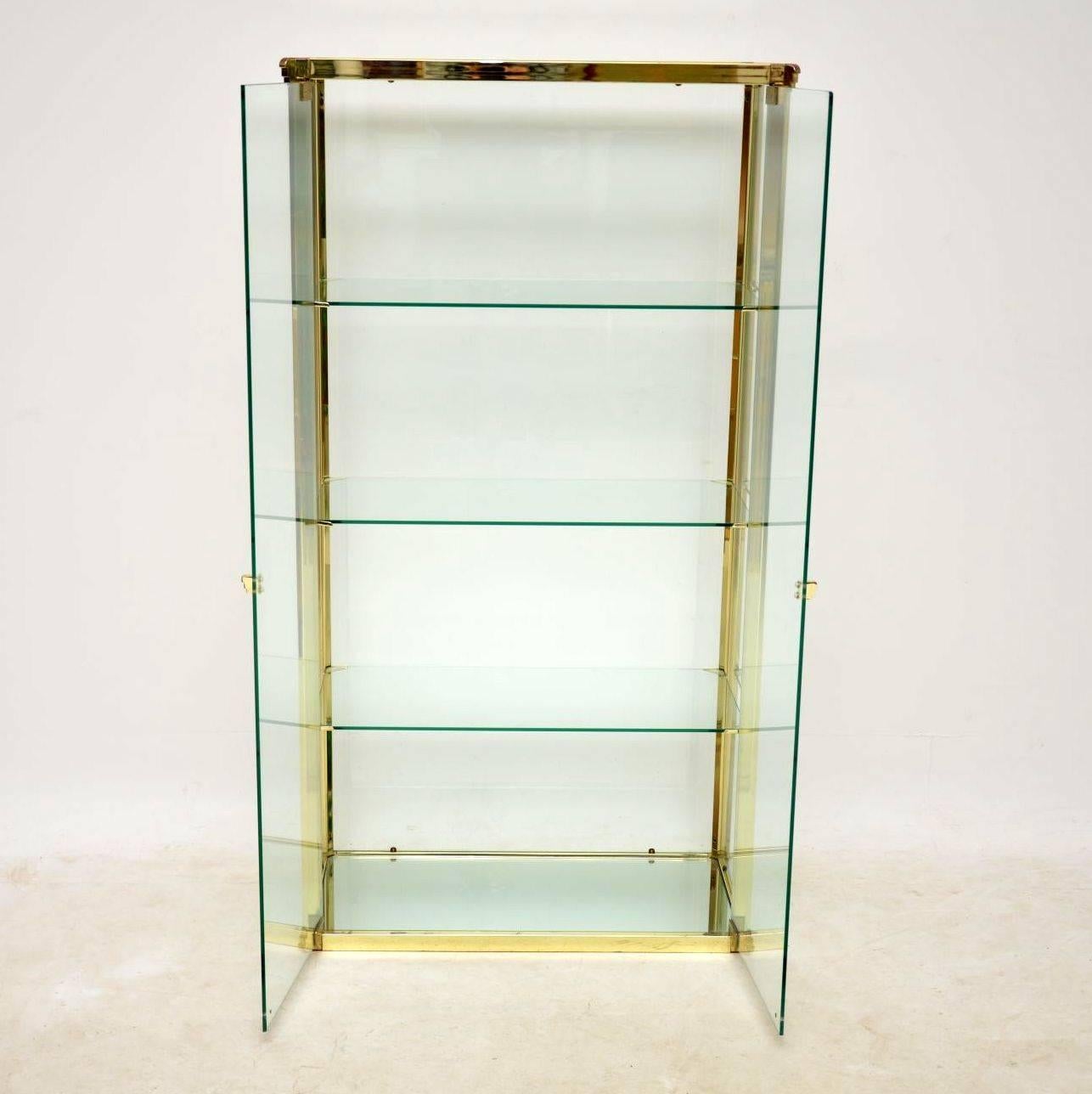 A stunning and very unusual vintage glass display cabinet, this was made in Italy, it dates from the 1970s. It has a brass frame, brass handles and brass shelf supports, with a clear glass carcass and shelves, the bottom shelf is mirrored glass. The