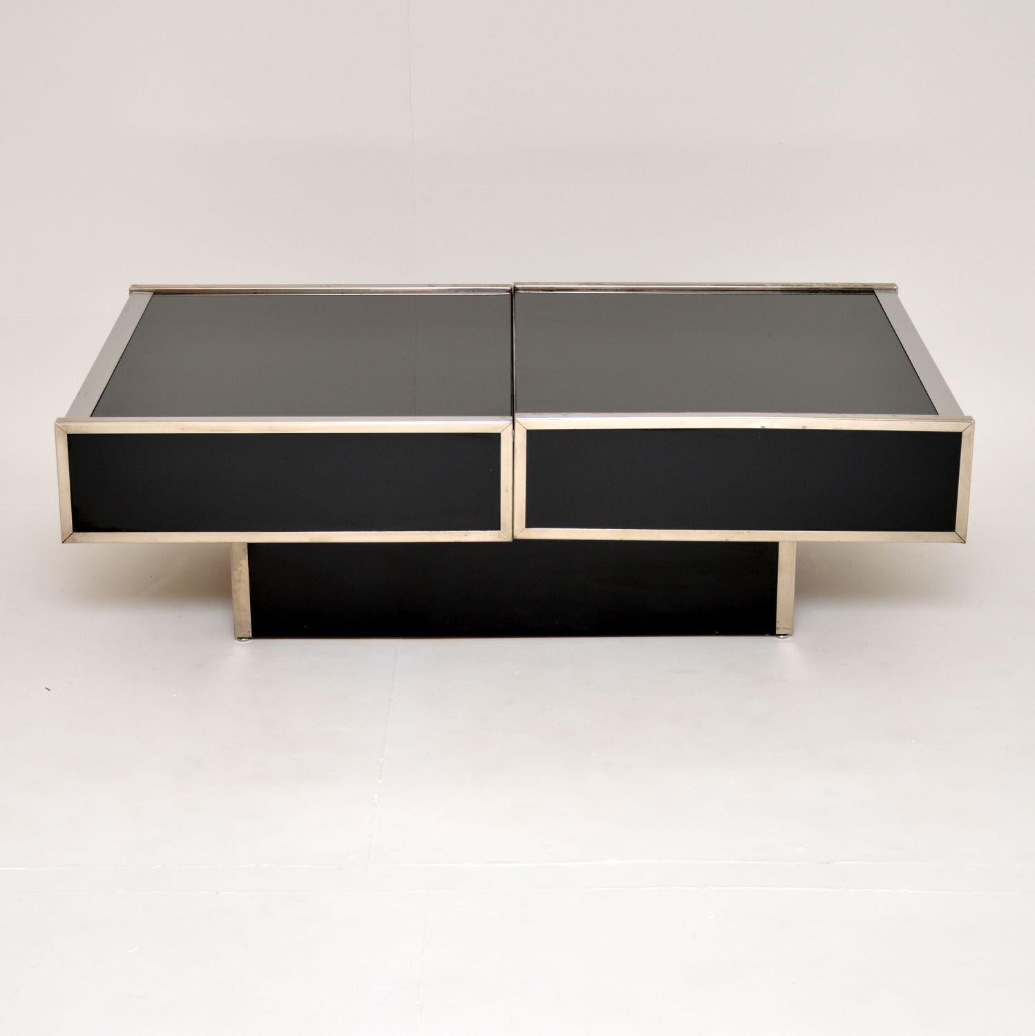 An absolutely fabulous vintage coffee table with a hidden dry bar compartment. This was made in Italy around the 1970’s, it was possibly designed by or is in the manner of Willy Rizzo.

It’s very well made with a black glass top, black formica