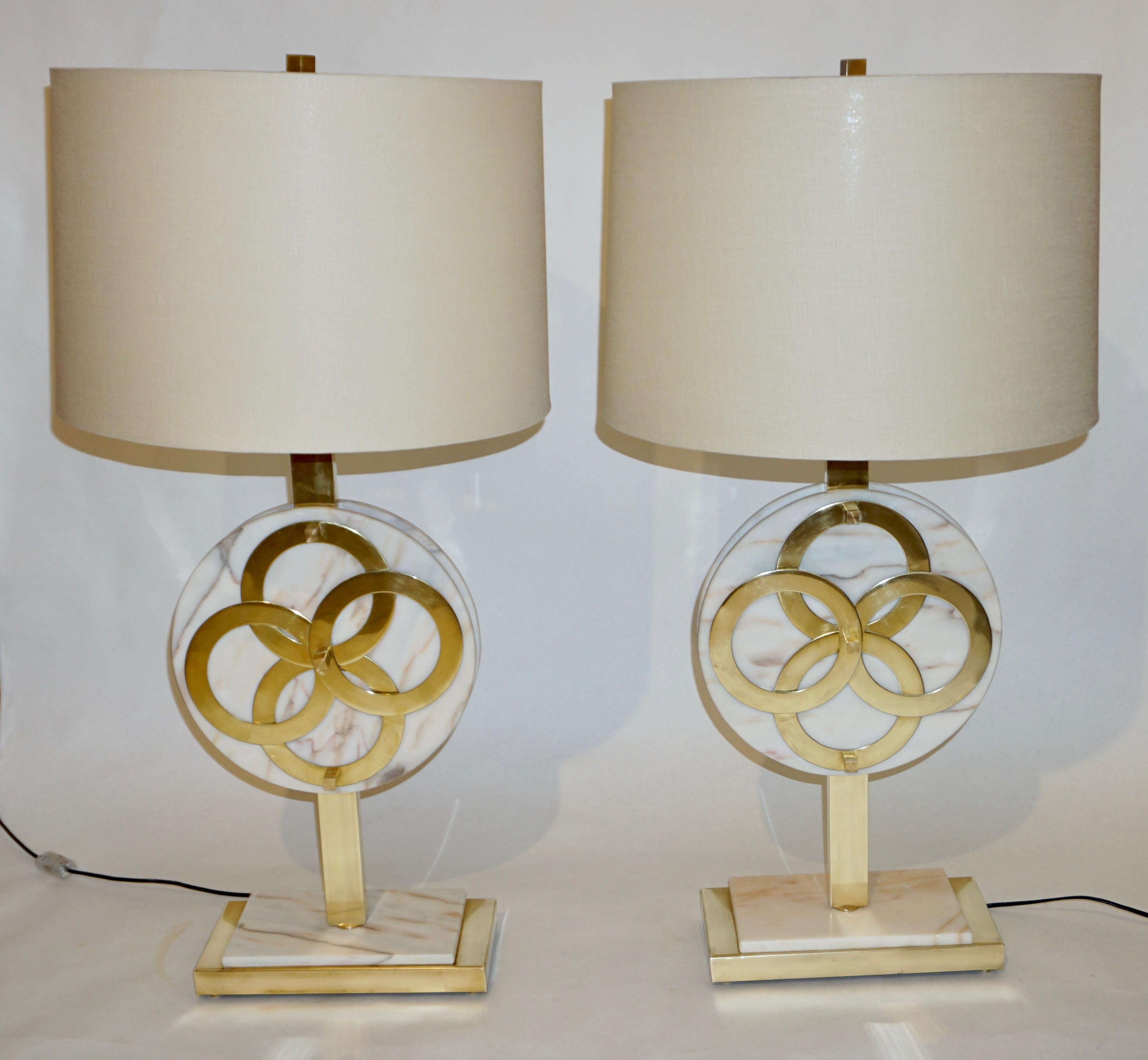 Mid-20th century Italian pair of table lamps, unique geometric design, entirely handcrafted in brass and pink Carrara marble, the body consisting of two hand polished marble discs, embracing a brass pole and decorated on one side with two brass