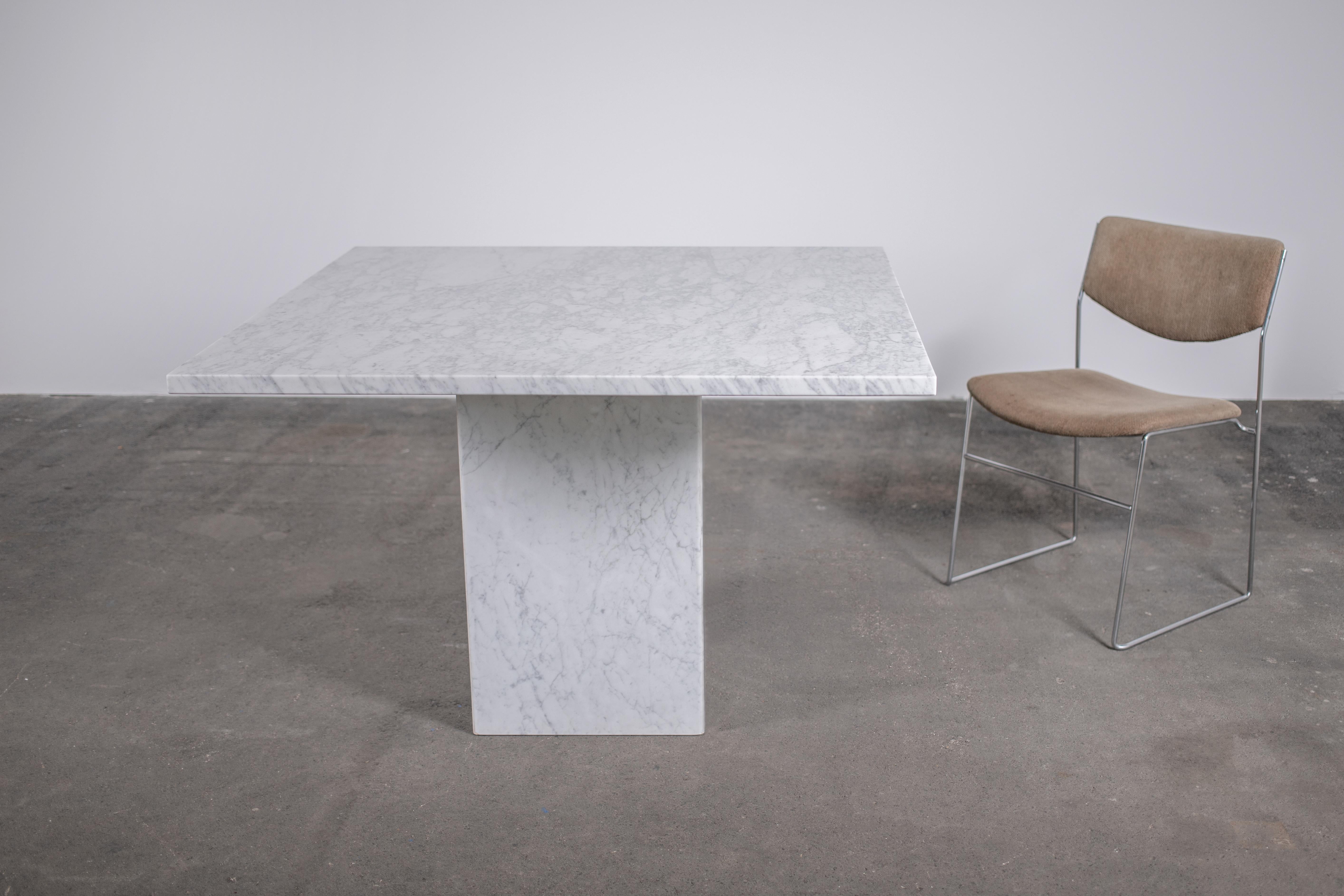 Monumental 1970s vintage Italian white Carrera marble dining table in Brutalist square format with single square leg, also in white Carrera marble. Thick 1 inch (3cm) slab sits atop a base of 4 mitered slabs of the same marble.

Marble is in very