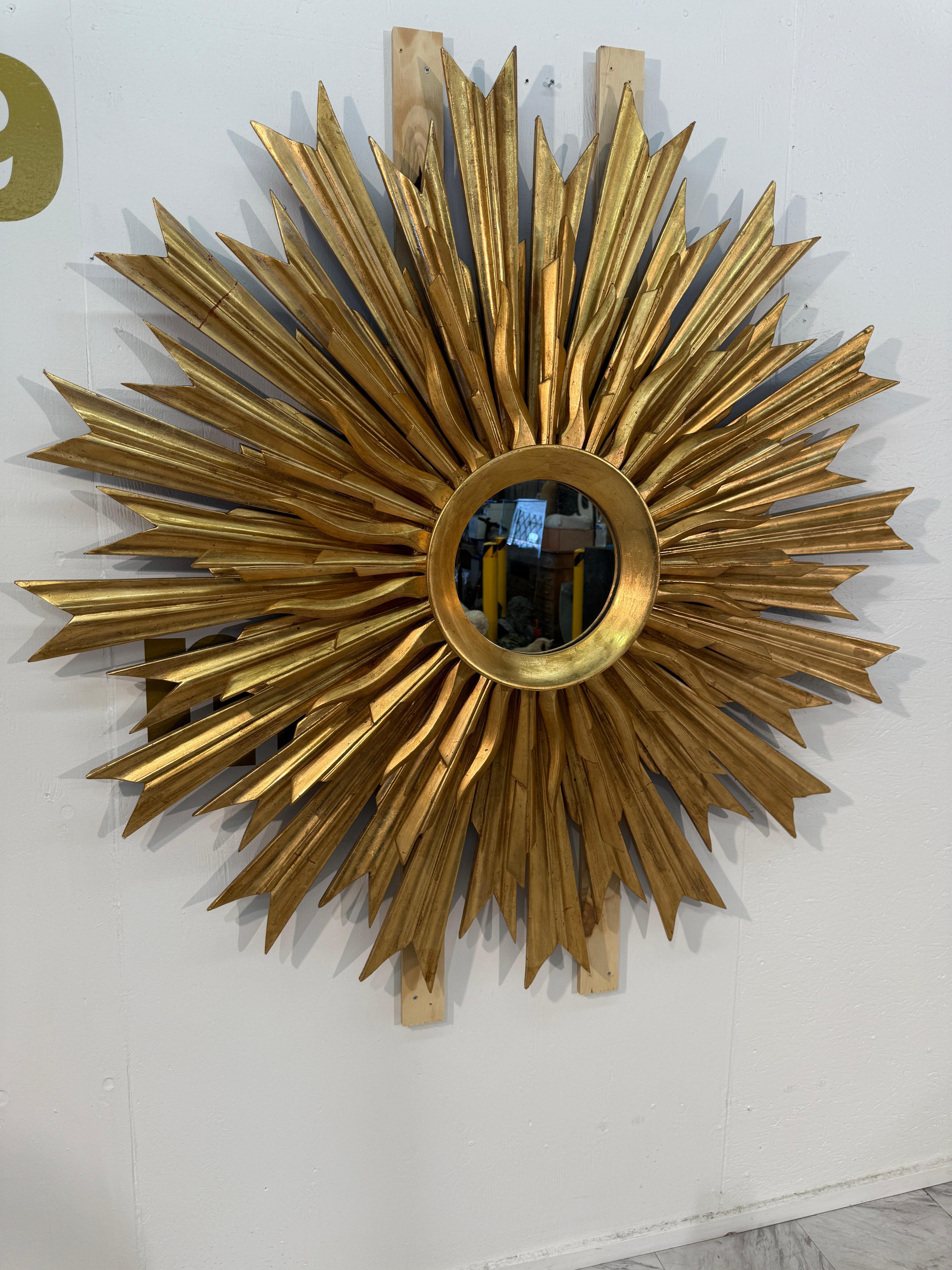 Este llamativo espejo de pared presenta un elaborado diseño de rayos de sol, con un espejo central circular rodeado por un conjunto de rayos alargados y afilados. Cada rayo está meticulosamente tallado con facetas angulosas, creando un efecto