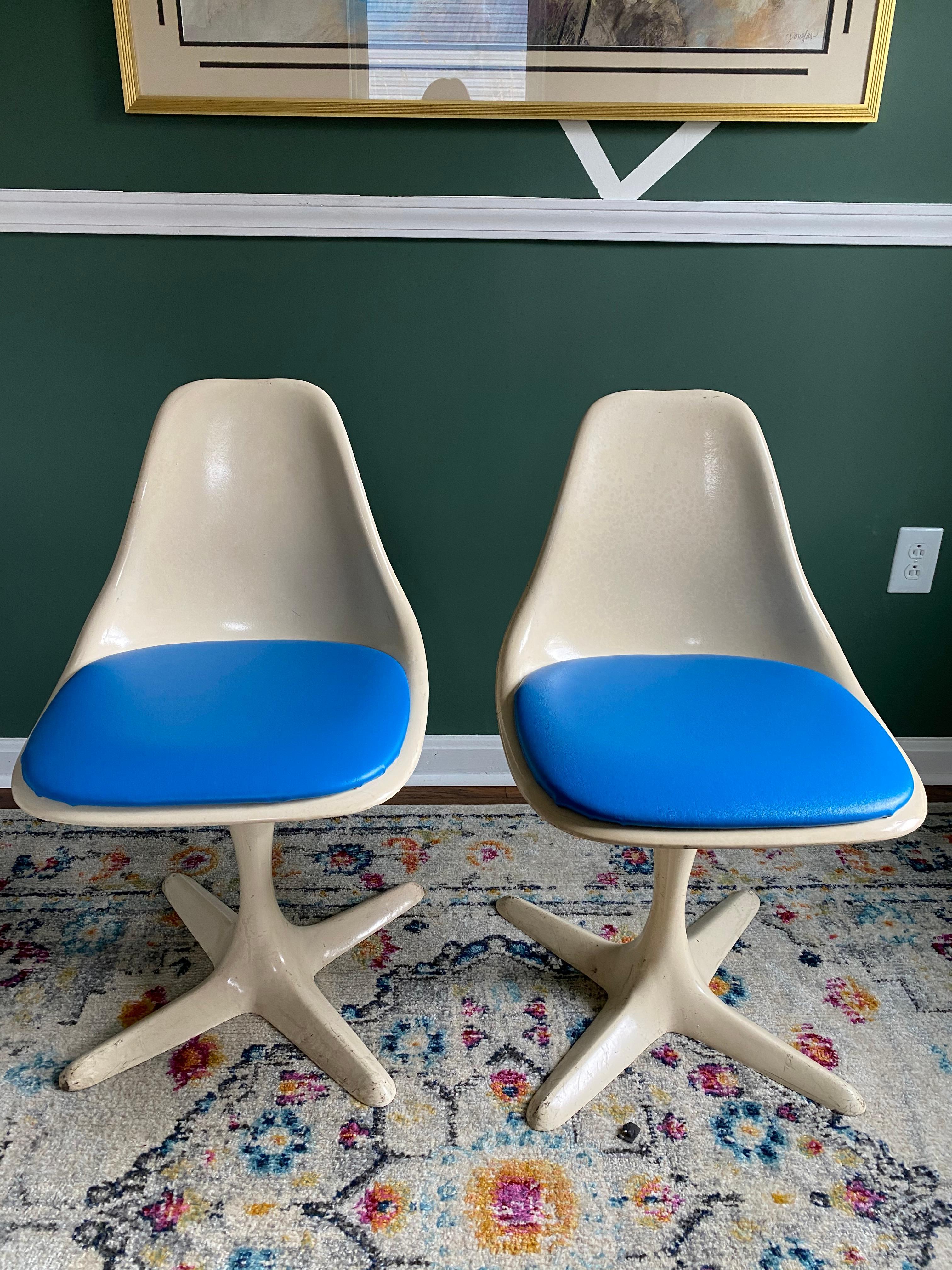 A pair of 1970s tulip chairs with propeller bases designed by Maurice Burke. These chairs feature white fiberglass shells, blue cushions and white enamel aluminum propeller bases. These chairs need to be restored, including the bases and cushions.