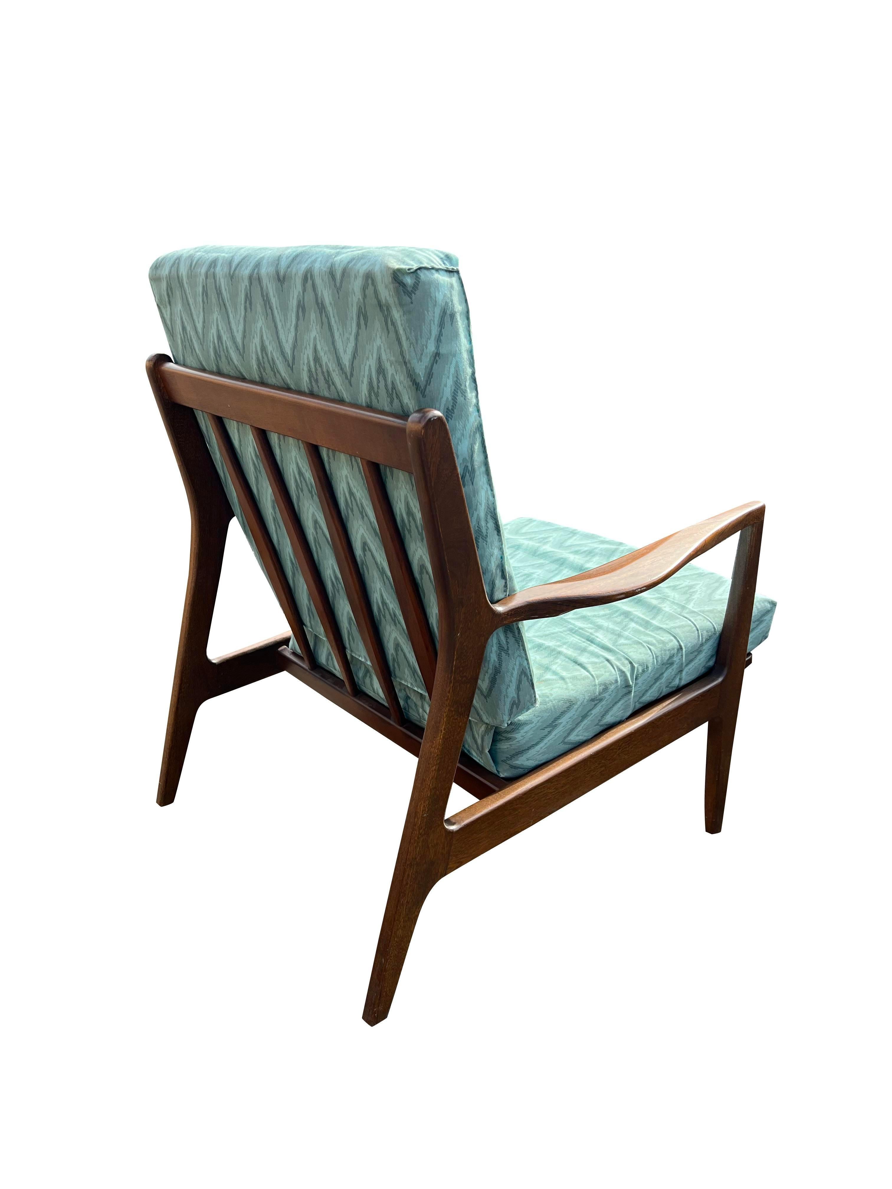 This vintage mid-century modern lounge chair is a stylish and comfortable piece of furniture. Its distinctive slat back and curved arms offer both aesthetic appeal and ergonomic support. The chair's sturdy wooden frame and comfortable upholstery