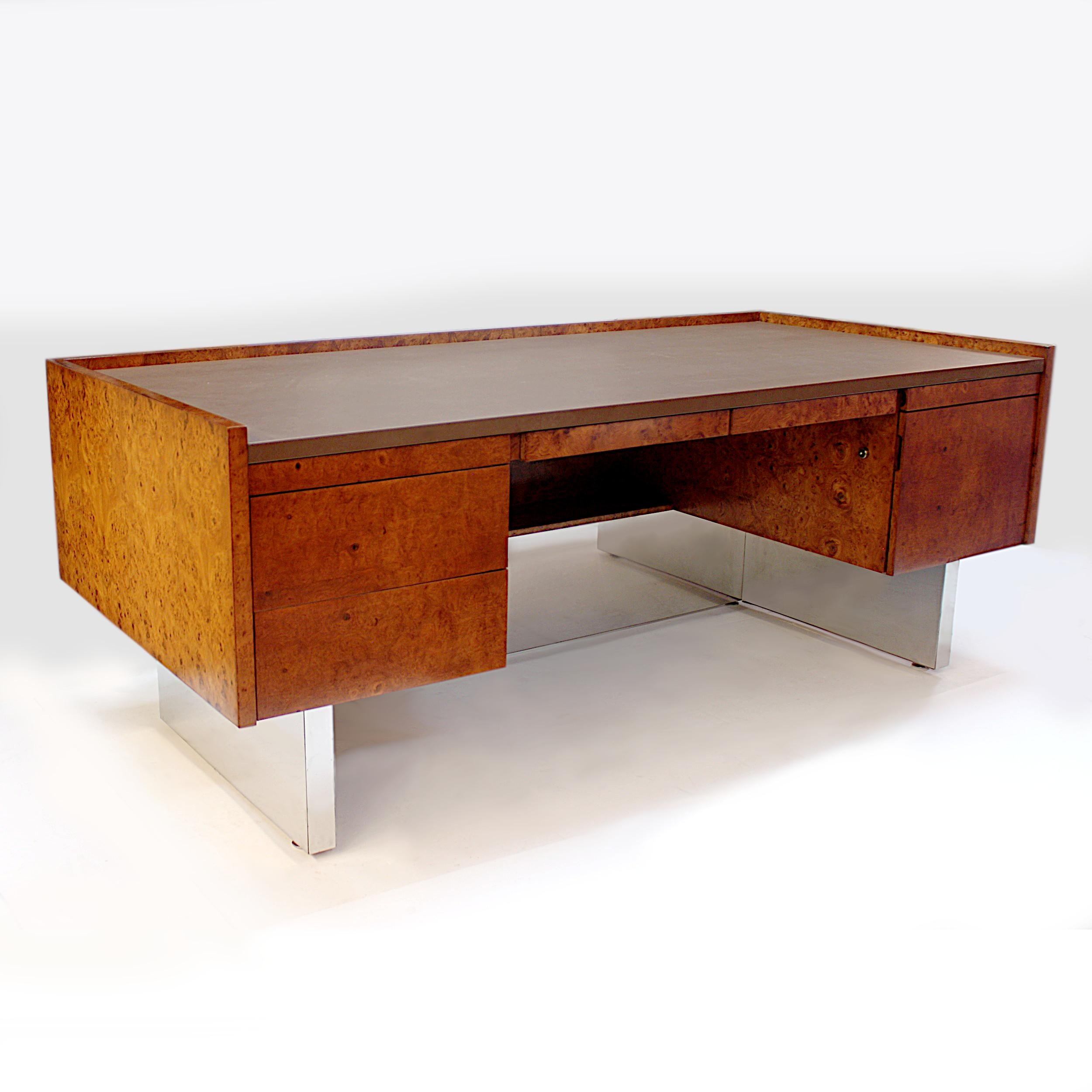 Amazing 1970s executive desk by Biltrite Furniture Mfg Inc of Montreal, Canada. This sleek, slab-sided, desk features gorgeous, book-matched olivewood veneer, Leather writing surface, chrome pedestal base, and a unique minimalist design that makes