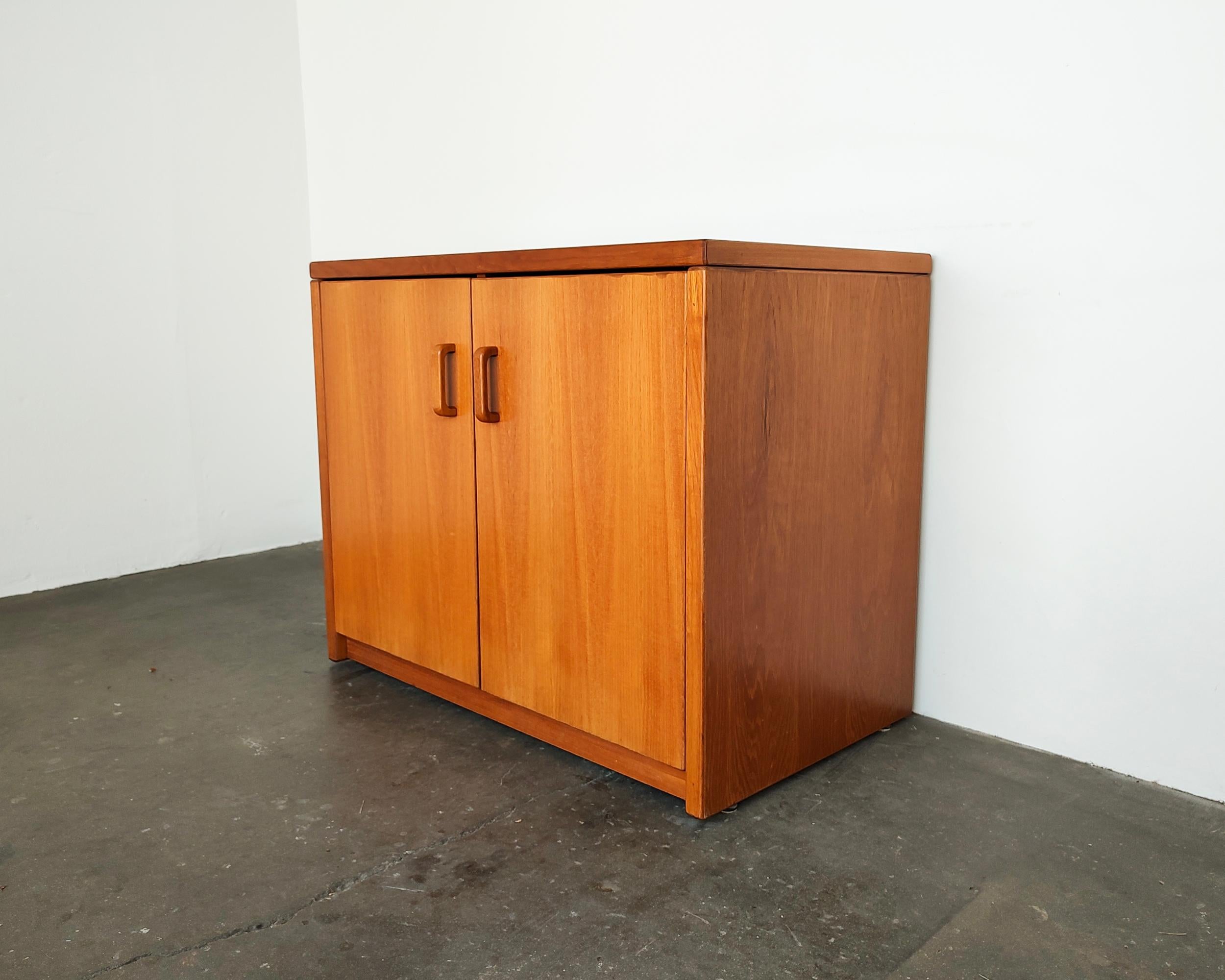 1970s small teak wood cabinet with split interior and adjustable shelves inside. Beautiful minimal design with solid teak pulls. Overall great condition, some light wear present consistent with vintage age.

36