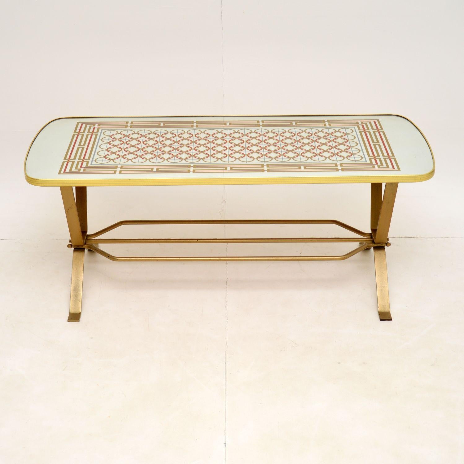 A stylish and interesting vintage coffee table, made in England and dating from the 1970’s.

This has a mirrored top with coloured geometric patterns, and a steel base with gold paint finish. The quality is excellent, this is well built and