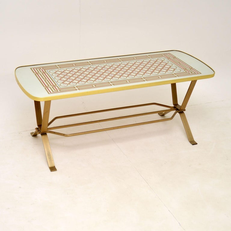 A stylish and interesting vintage coffee table, made in England and dating from the 1970’s.

This has a mirrored top with coloured geometric patterns, and a steel base with gold paint finish. The quality is excellent, this is well built and