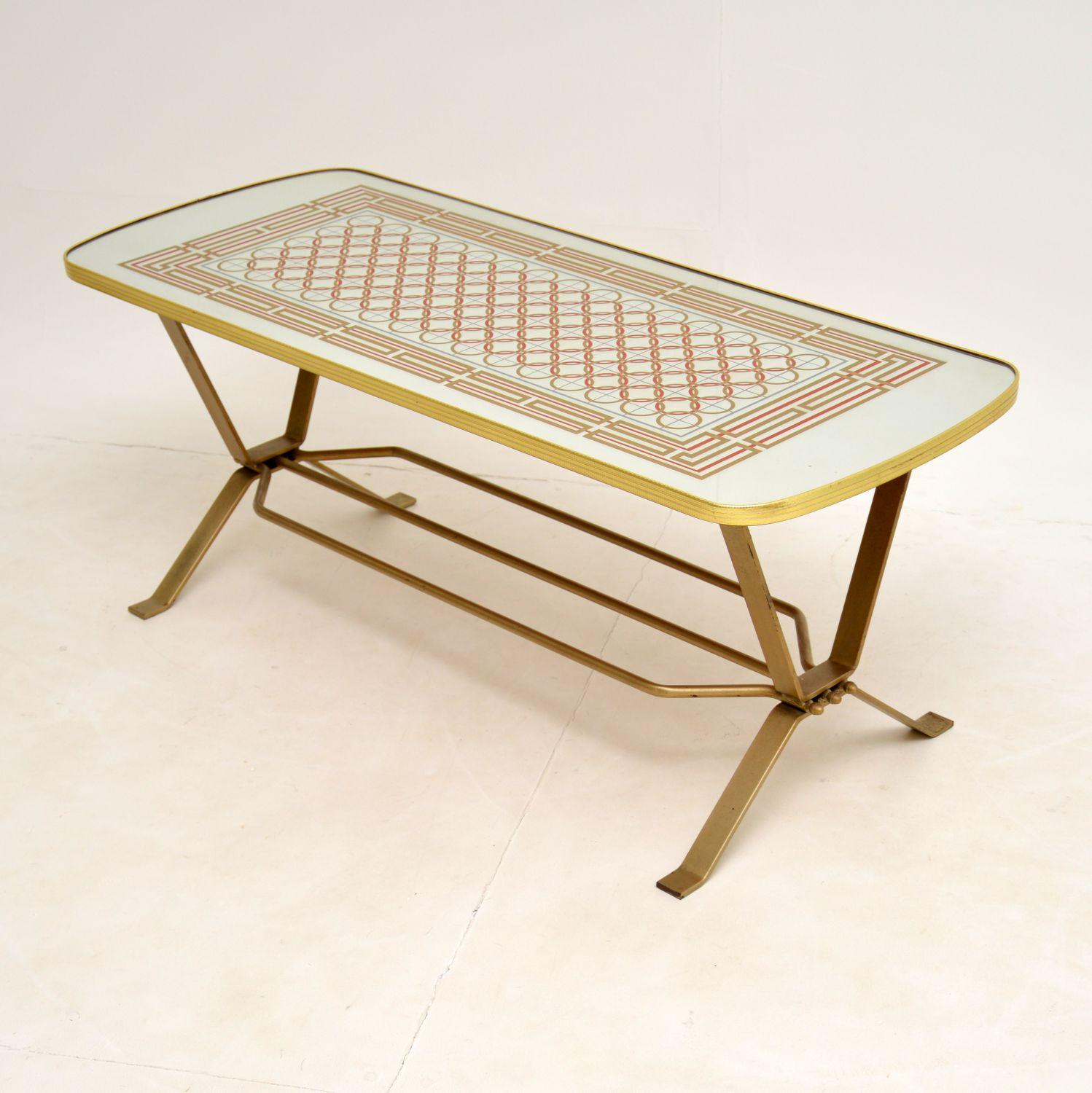 A stylish and interesting vintage coffee table, made in England and dating from the 1970’s.

This has a mirrored top with coloured geometric patterns, and a steel base with gold paint finish. The quality is excellent, this is well built and sturdy.