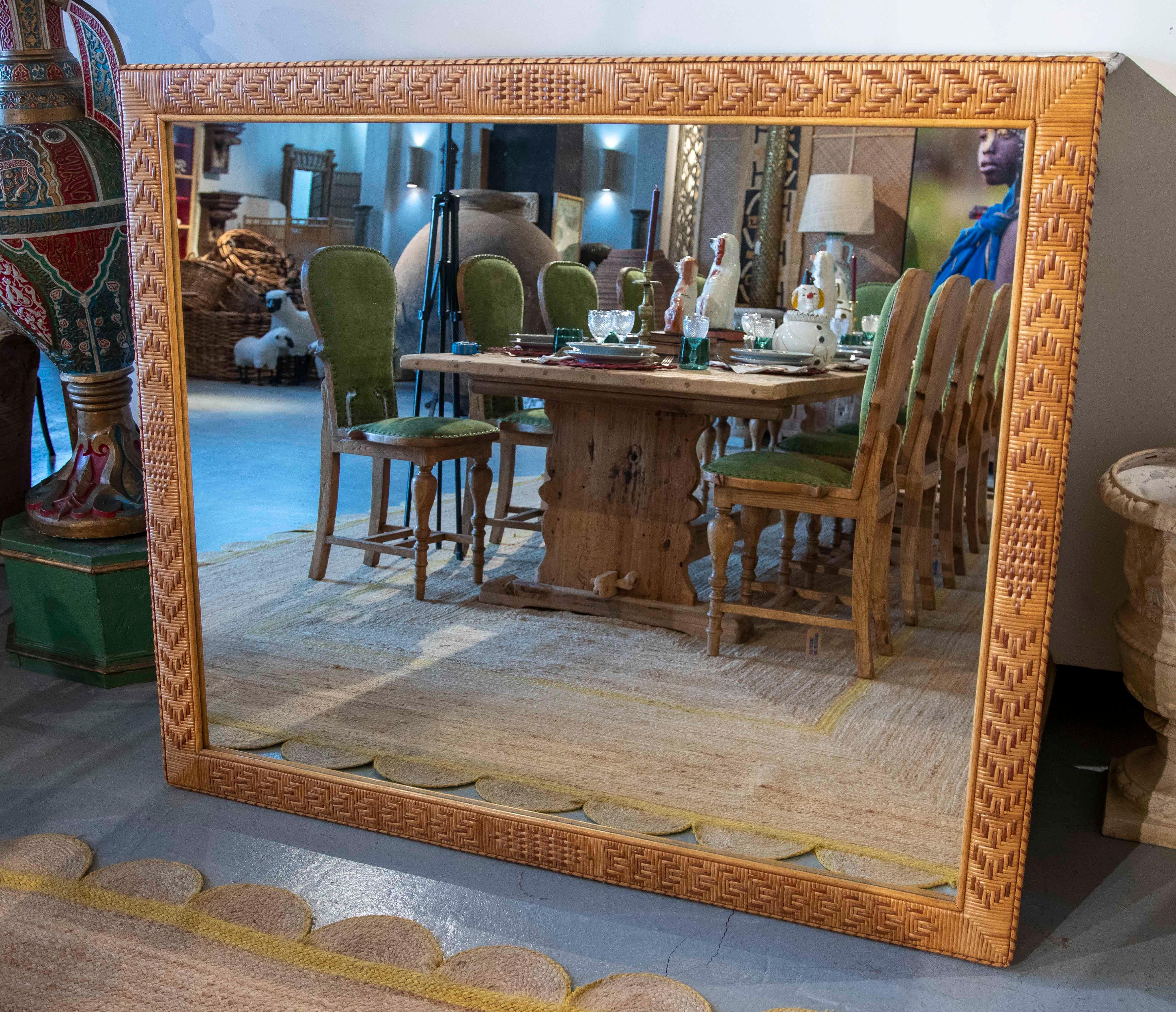 Grand miroir rectangulaire avec un cadre artisanal en rotin tressé avec un motif géométrique croisé. Le tissage méticuleux ajoute de la texture et de la chaleur naturelle à l'objet, idéal pour les espaces de style bohème, côtier ou méditerranéen. Sa