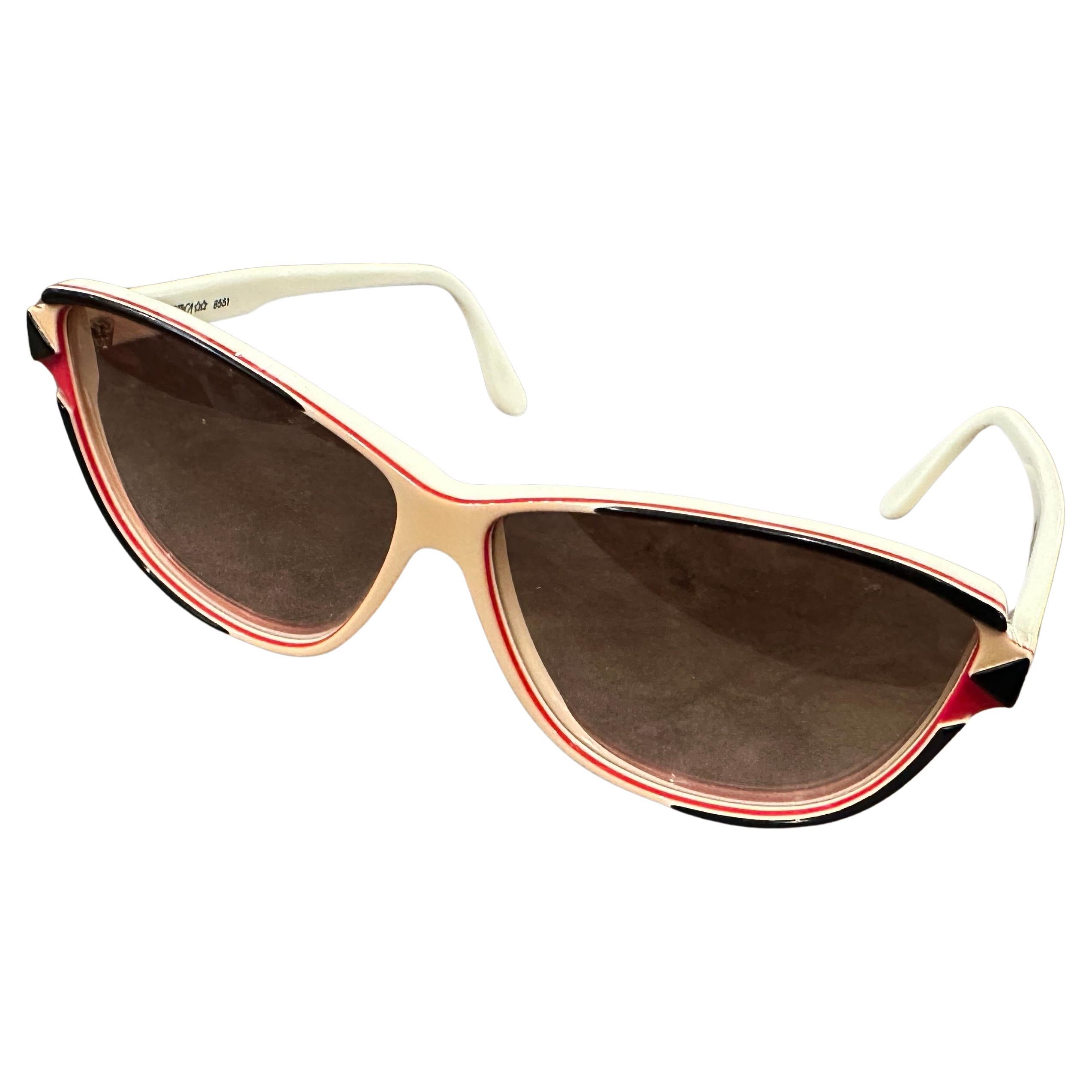 Adopta un estilo atemporal con estas auténticas gafas de sol de gran tamaño de los años 70 de Luxottica, fabricadas en Italia. Estas monturas vintage presentan una llamativa silueta inspirada en los ojos de gato con un exclusivo detalle tricolor en
