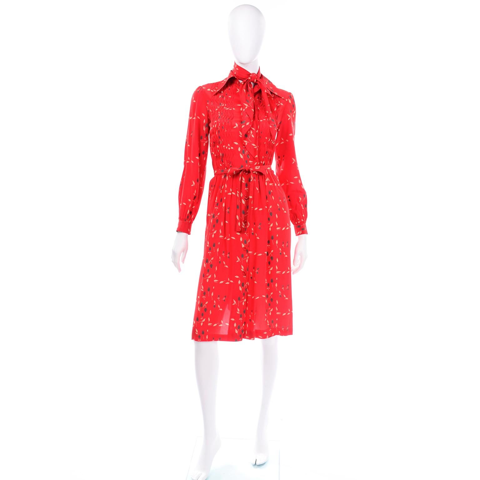 This is such a pretty dress from Albert Nipon in a red floral print and fabric belt and neck scarf or kerchief head wrap. This great 1970's day dress has a pointed collar, functional pockets, gathered long sleeves with cuffs and buttons down the