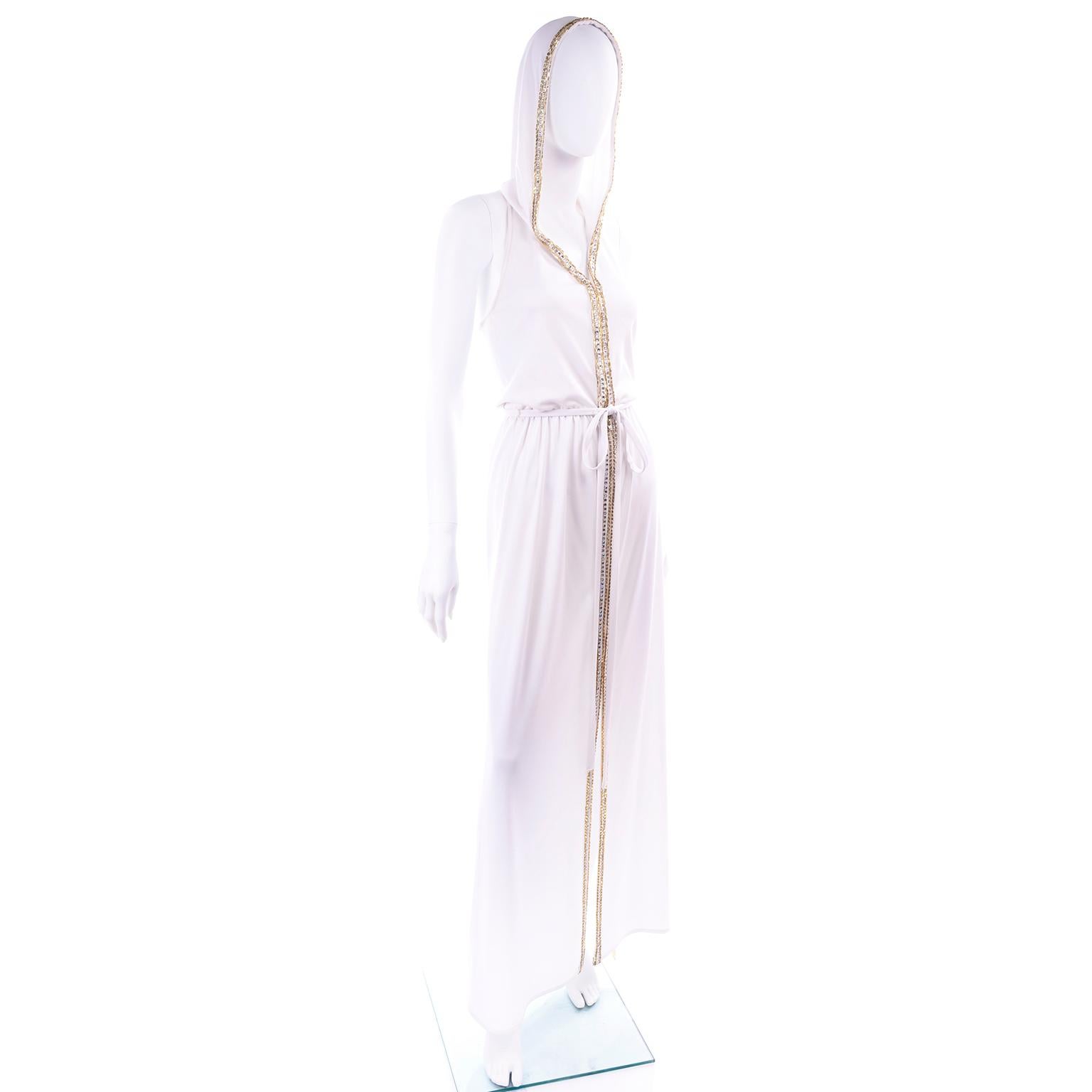 We fell in love with this vintage 70's maxi dress when we found it!  This 1970's full length white jersey vintage dress is trimmed with rhinestones and gold beads and the best part - it has a hood!  The dress zips up the front and has a high slit up