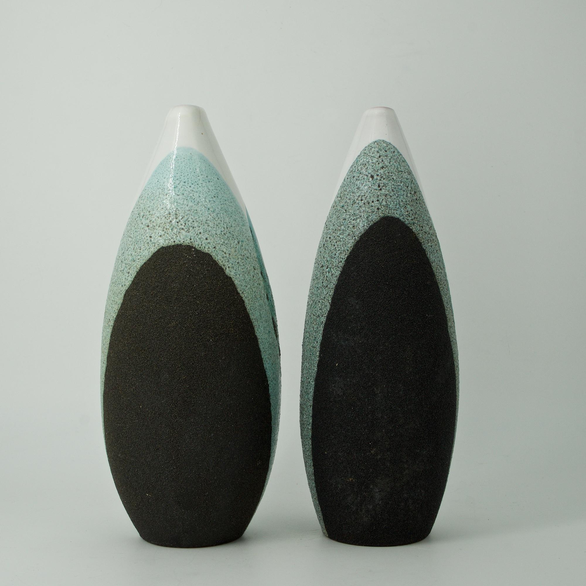 Pair of Bitossi Raymor ceramic vases, one with hariline to tip, and other with roughness to tip.
Measures: Diameter 3.75 x height 9.88 in. 
Measures: Diameter 4.25 x height 9.88 in.