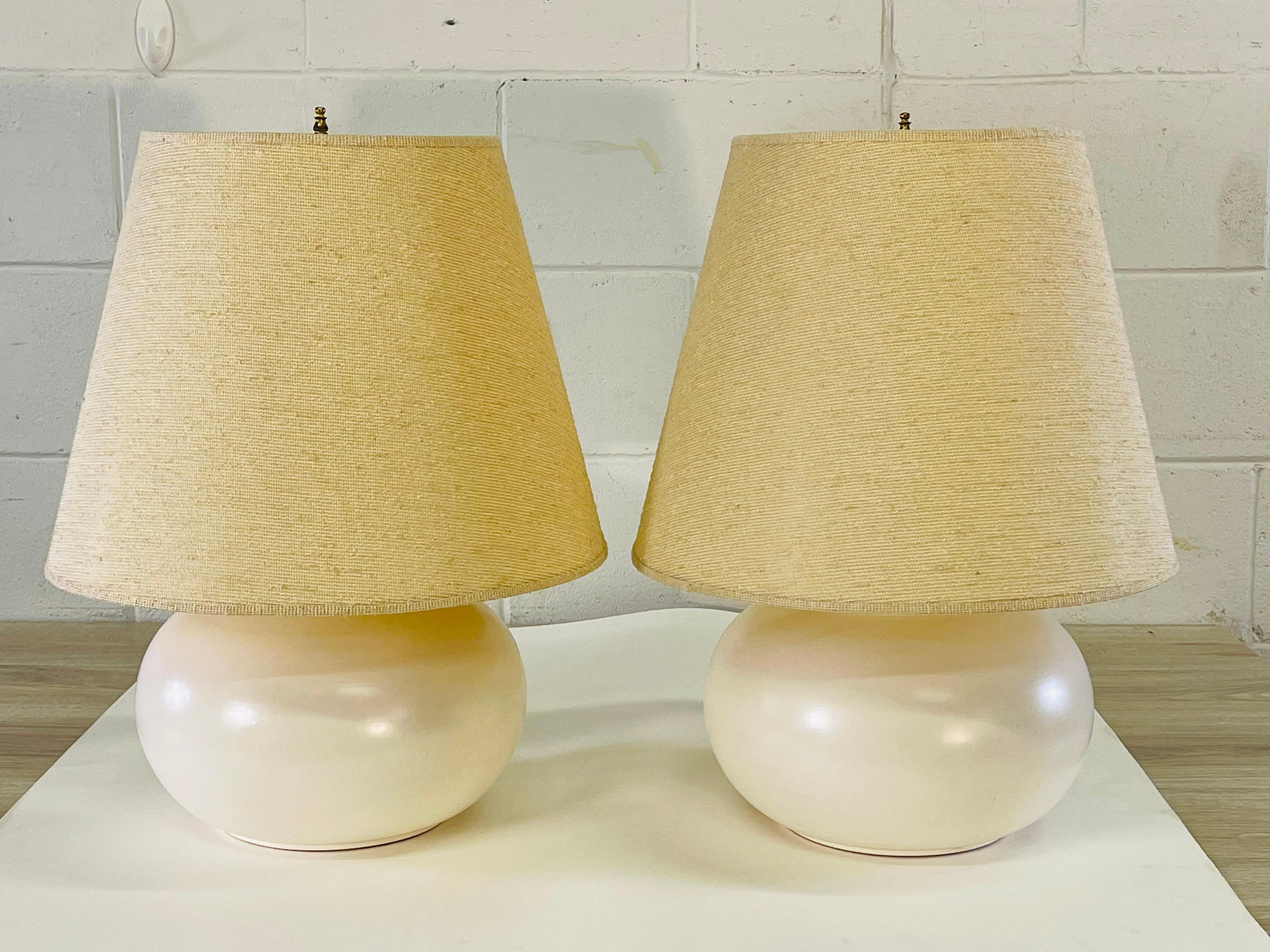 Vintage 1970s pair of white matte finished bulbous table lamps with the original shades by Haeger Pottery. Wired for the US and in working condition. Socket, 13.5”H. Harp, 4”diameter x 9”high. Shade alone is 15” diameter x 13” height. Lamps without