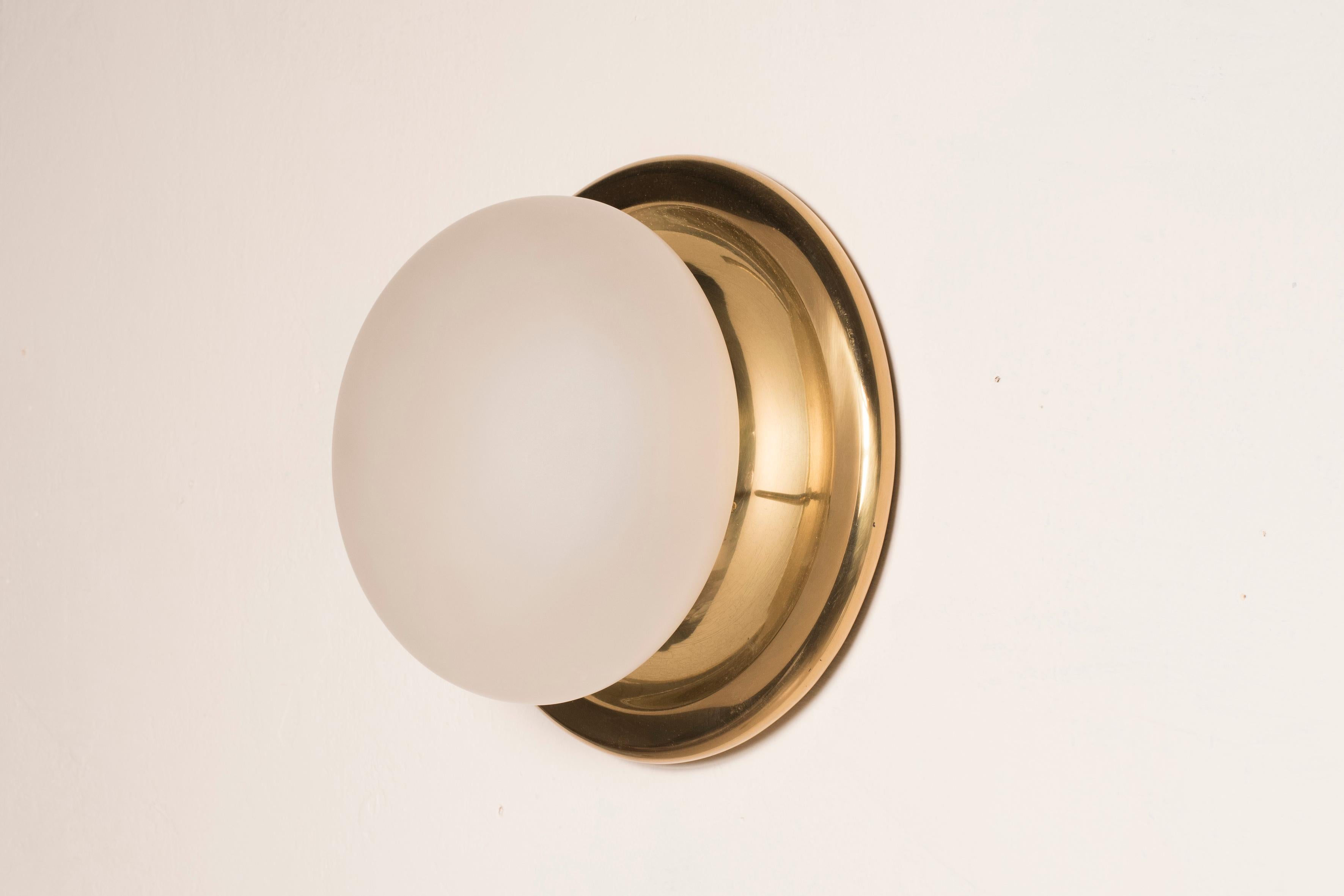 1970s white frosted glass wall lights with brass base 
8 available, price per item
Size: diameter 27 cm 
Rewired, ready to be hanged
The wall sconces come in excellent conditions no cracks in the glass, the brass comes in its original patina