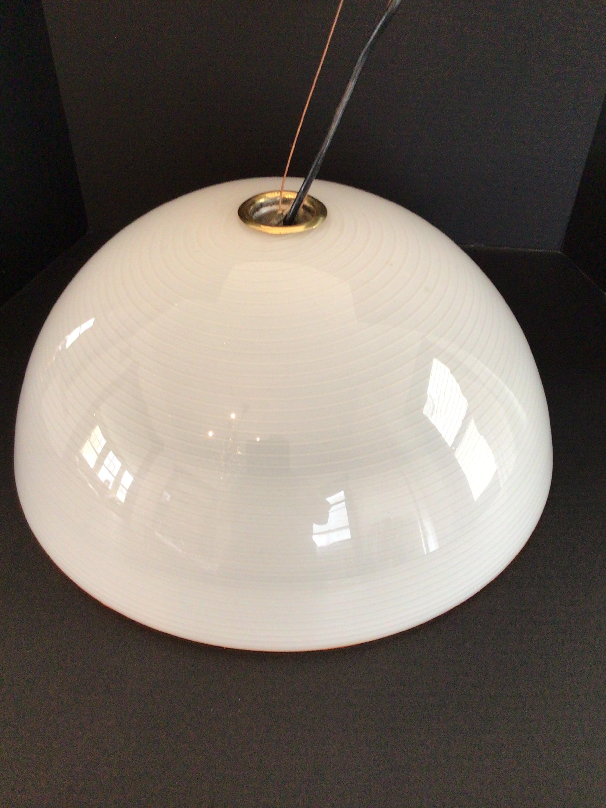 Colgante de cristal blanco de los años 70 con líneas circulares blancas y borde ámbar
Accesorios de latón
Viene con tejadillo acabado en latón (necesita pulirse)

Líneas circulares regulares/rectas, no arremolinadas como otras de aspecto similar.