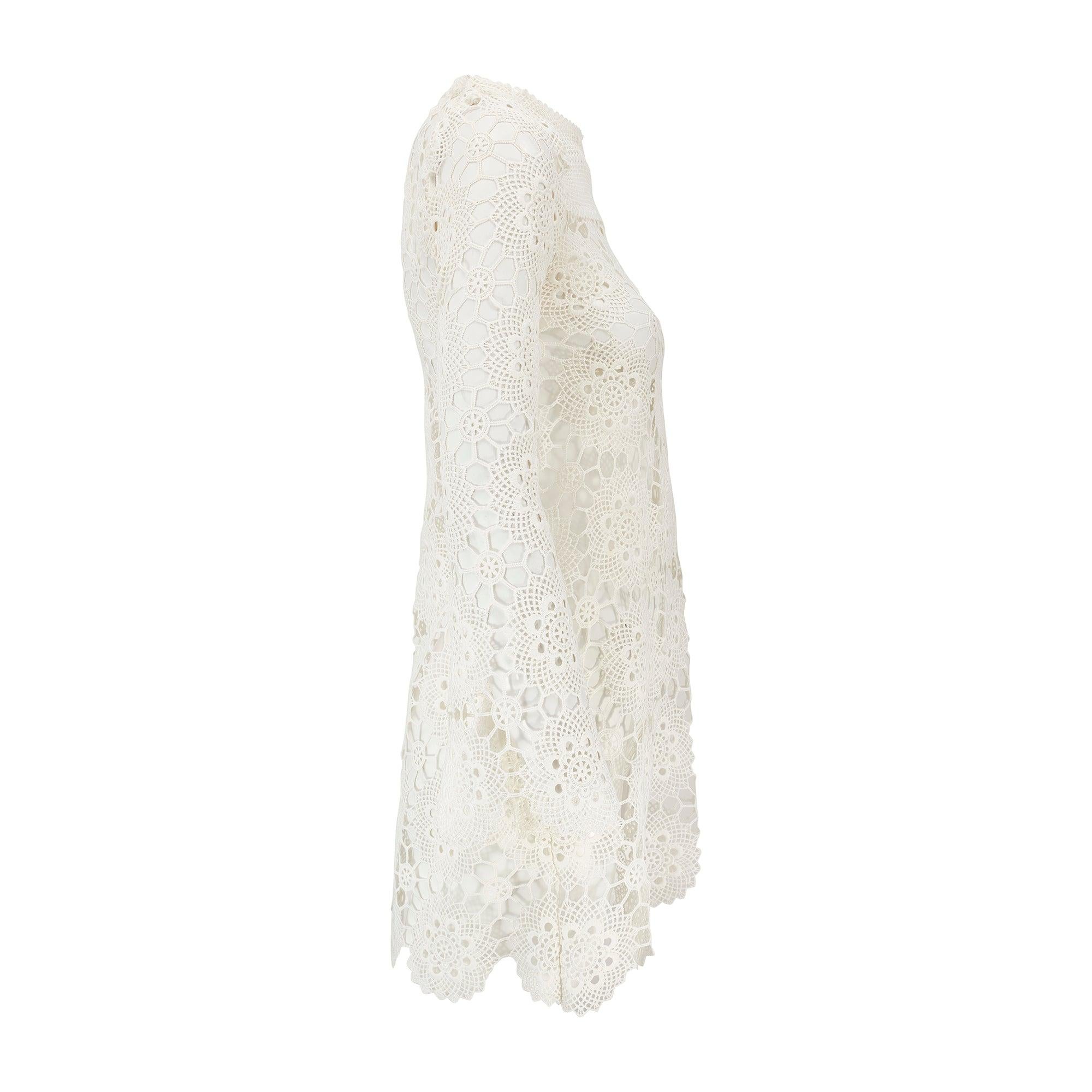 This bohemian mini-dress was crafted in the 1970s by an unknown designer. Crafted entirely from crochet and therefore completely see-through, it has a wide neckline with swinging, flared angel-sleeves. Woven from white manmade thread, the crochet