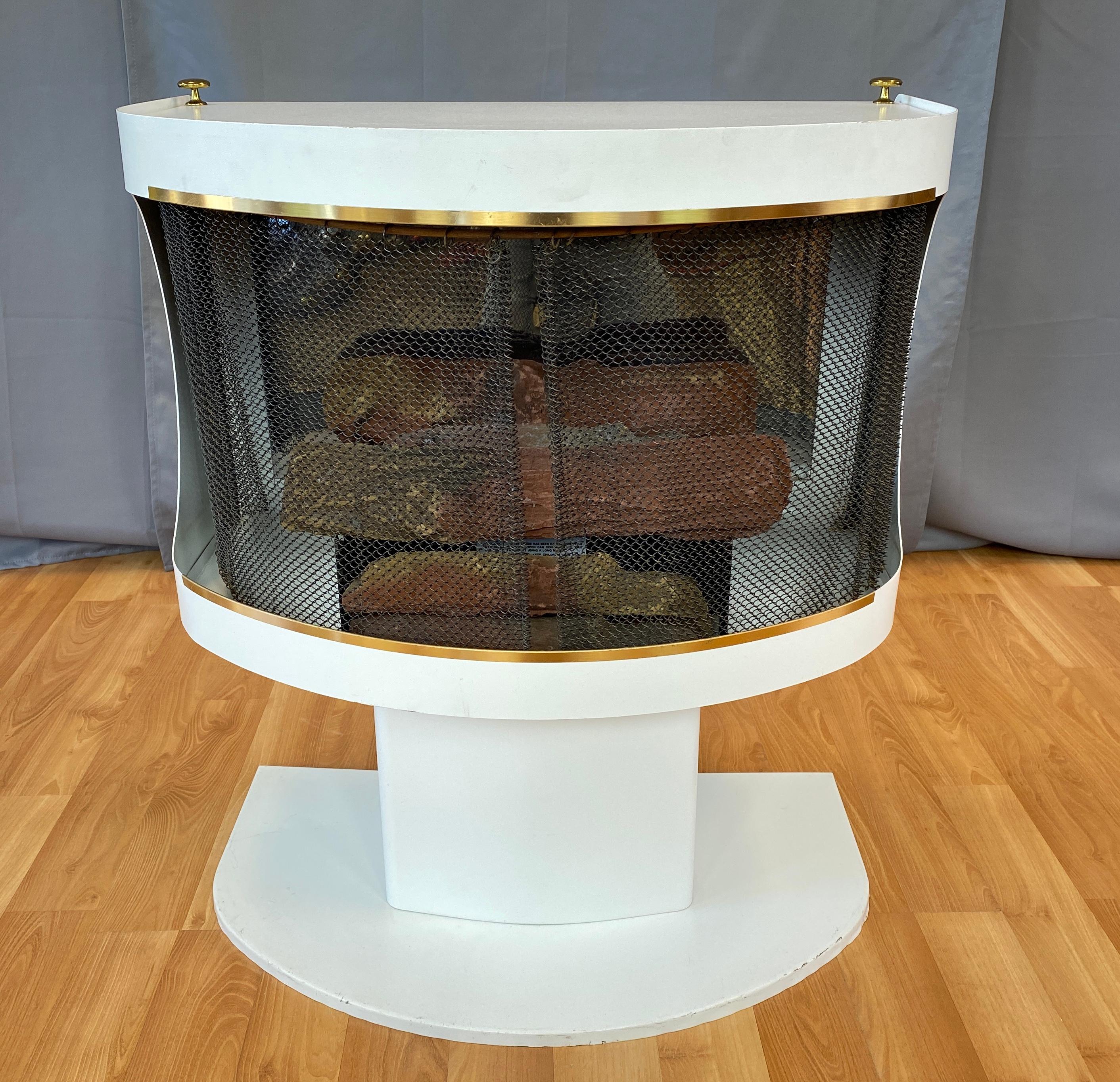 Offered here is a 1970s white free standing smokeless fireplace by Mastercraft Metal.

Main body sits on a pedestal stand, open up the sliding chain curtain, you have a burner box that would hold cans of
gel Sterno fuel, you cover that black box