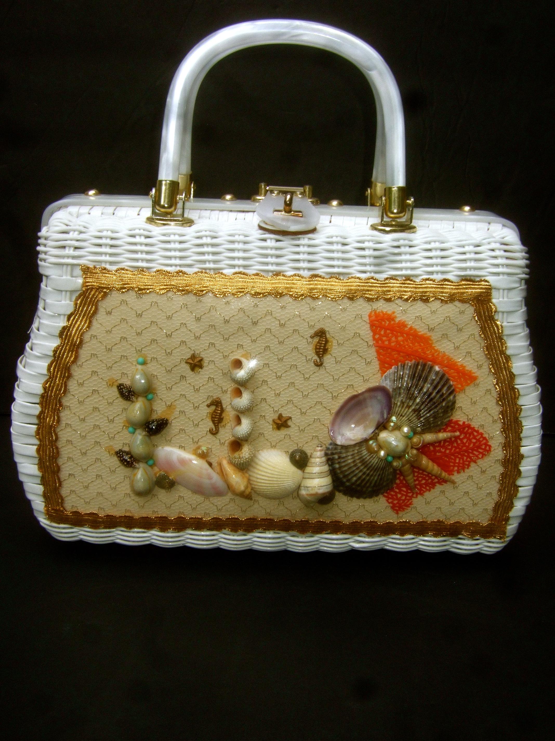 1970s Crisp white wicker sea life coastal handbag 
The charming woven white vinyl wicker handbag is embellished with a collection of organic seashells, faux seahorse figures and faux coral branches encased in a clear vinyl window on the front