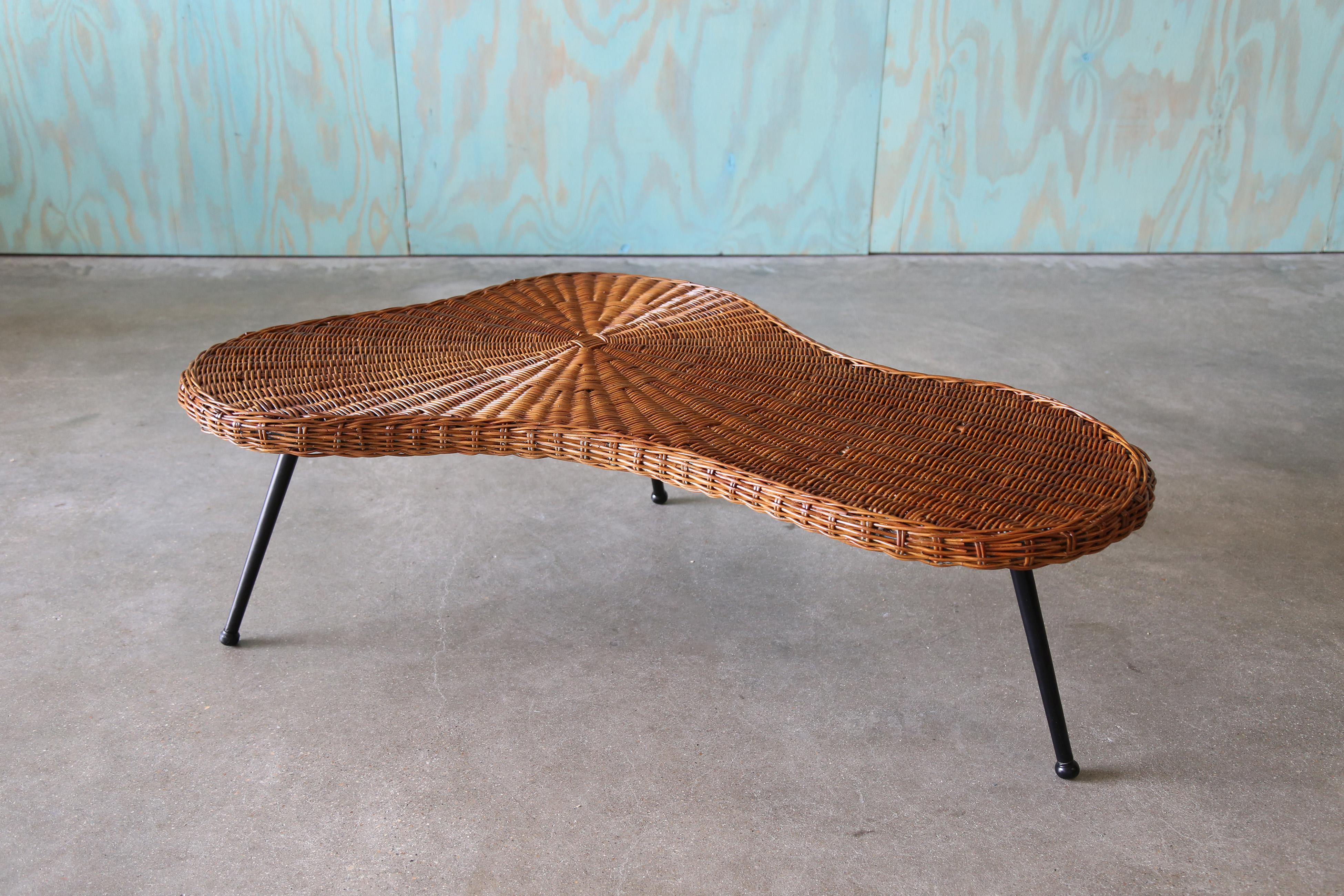 Table basse des années 1970 en forme d'amibe organique, avec un plateau en osier tressé sur une base en pin massif soutenue par des pieds en fer.  D'apparence française, le top rappelle les designs organiques de By Design Modern et de Vladimir