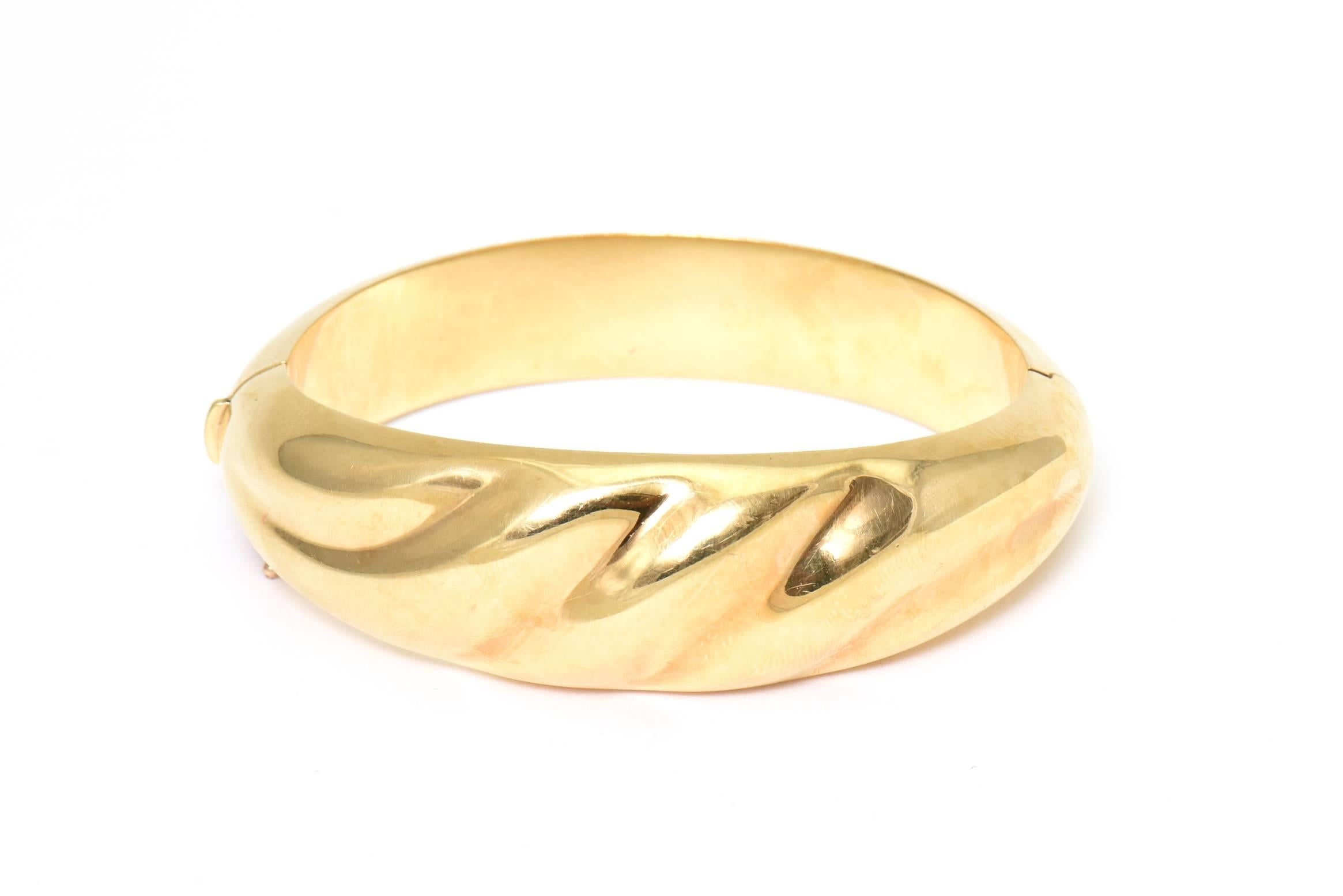 1970s Hinged 18k yellow gold bangle bracelet with a 3 dimensional wave design.  This bracelet was cast in Italy.  It has a push button clasp as well as a figure 8 safety.

Interior circumference 6.5
