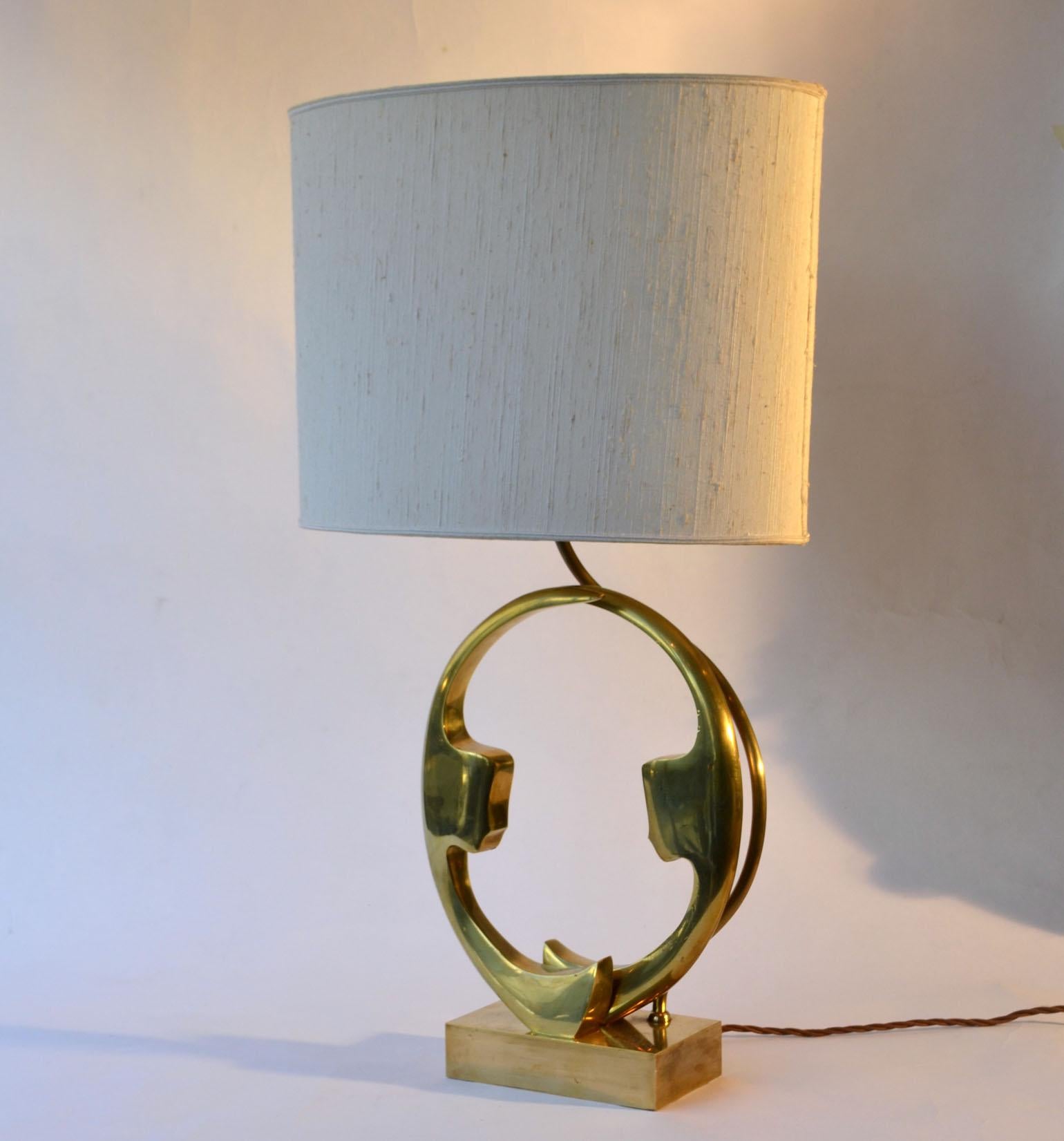 Single brass and bronze cast table lamp signed Willy Daro, Belgium 1970s picturing two female silhouettes faces facing each other on an oval ring. with original oval lampshade.
Belgian artist Willy Daro founded his factory 