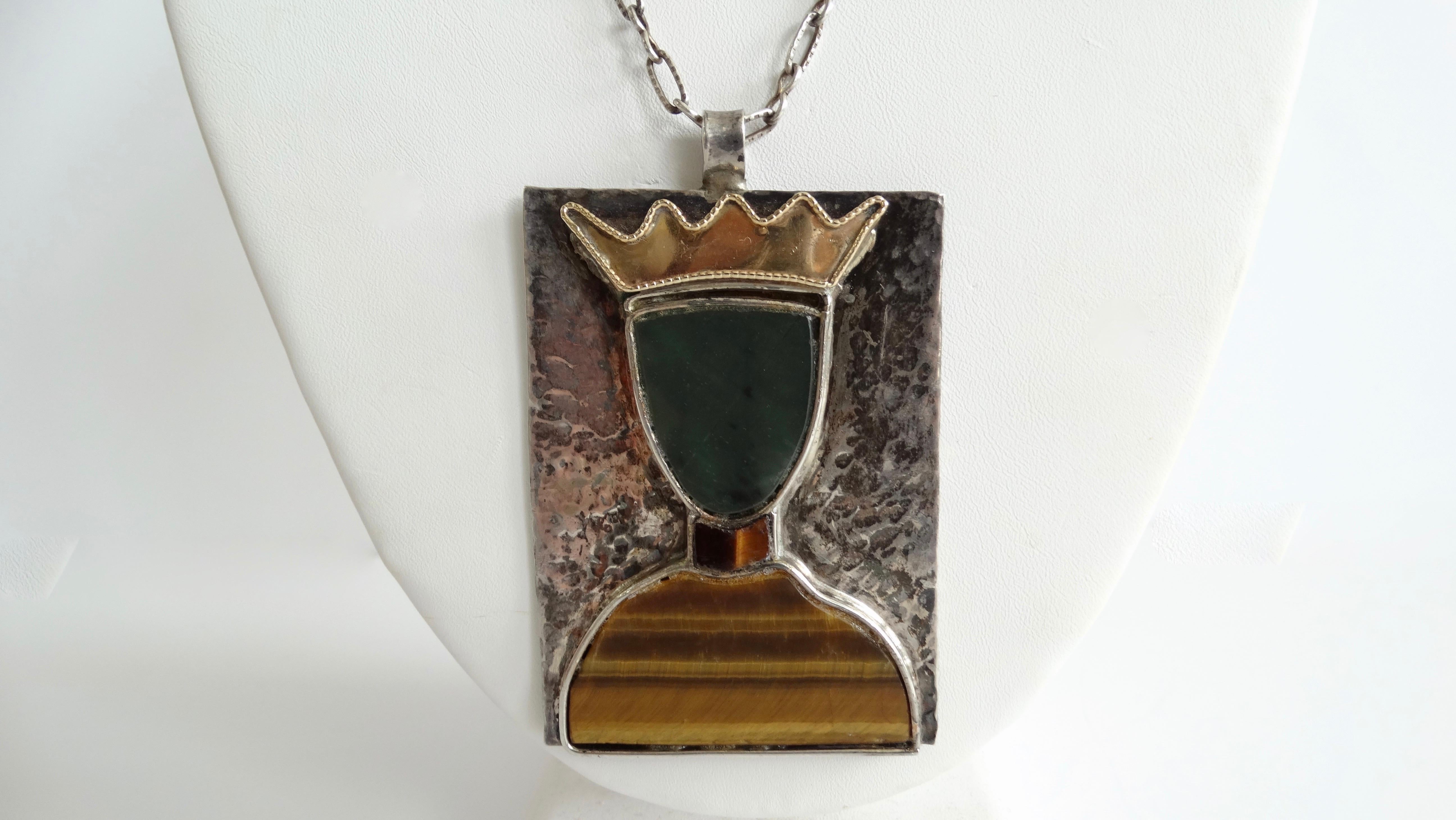 Score yourself a piece of true vintage with this William de Lillo necklace! Circa 1970s, this necklace features a pendant made of textured sterling silver with the silhouette of a queen. The queen is made up of 18k gold, tigers eye and jade. The