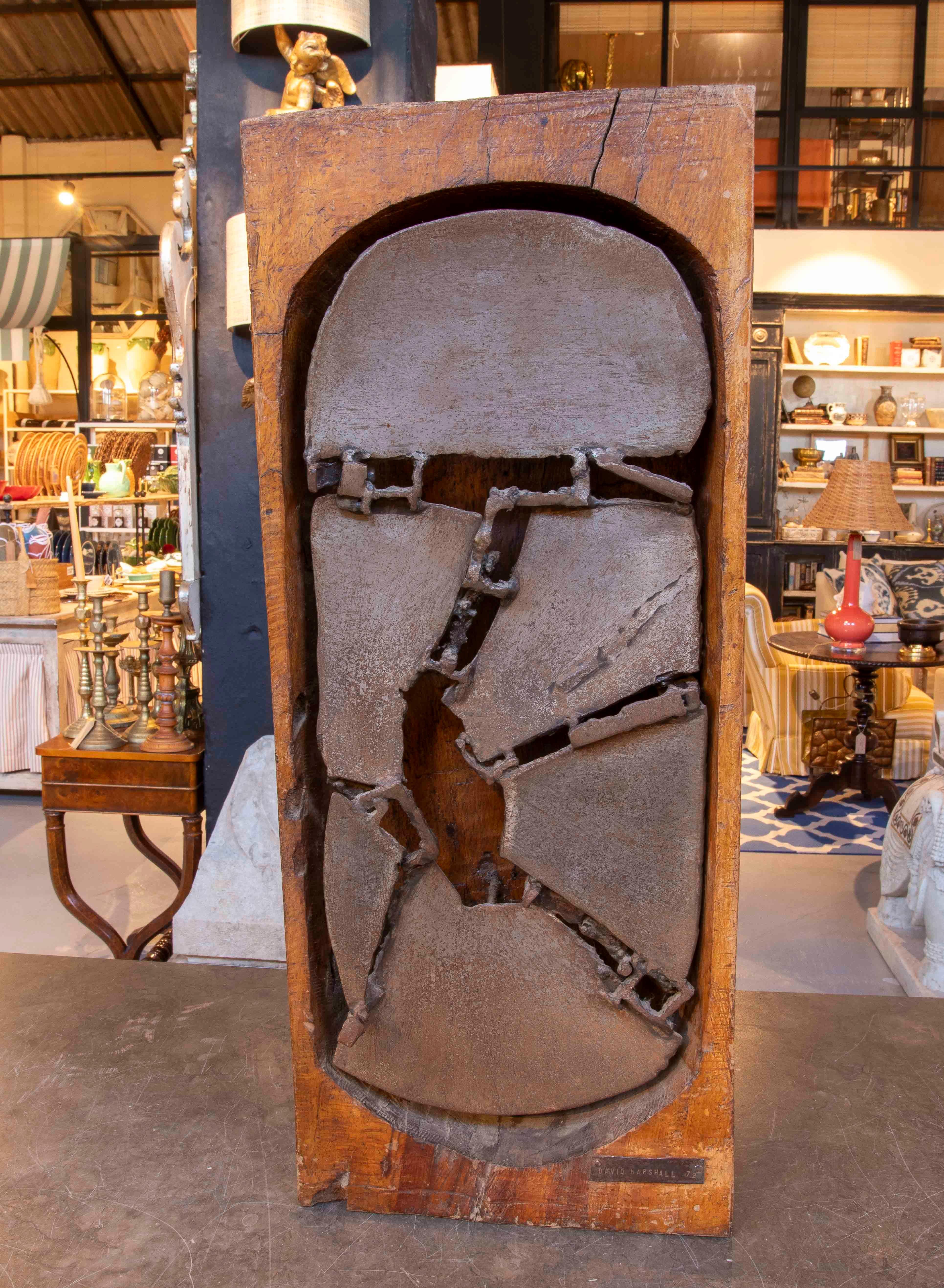 Un pezzo scultoreo firmato da David Marshall, datato 1972. Realizzata in legno massiccio con un inserto centrale in bronzo fuso, quest'opera combina forme organiche frammentate con elementi assemblati in una composizione dalla forte presenza