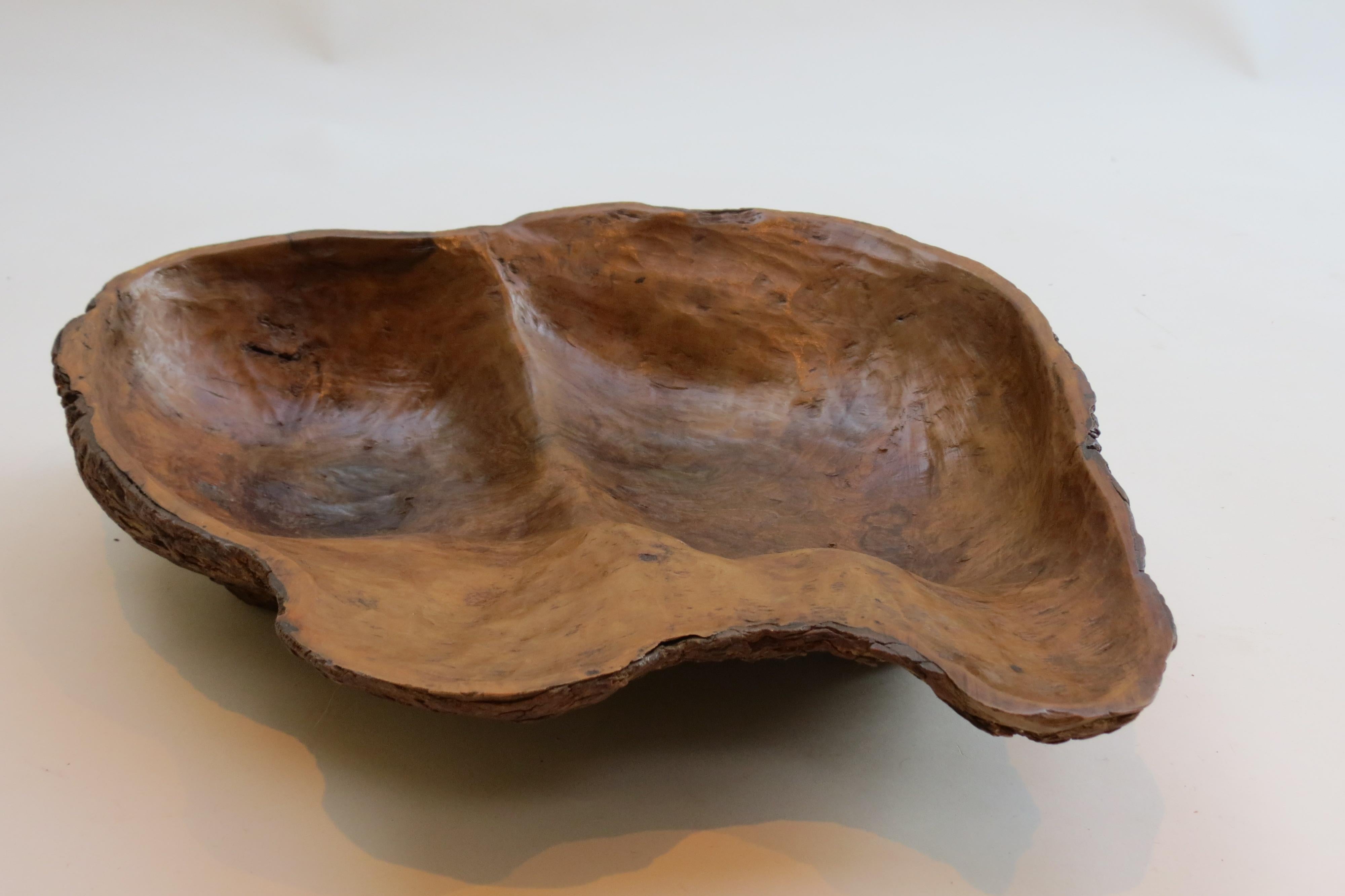Wooden bowl from the 1970s made from olive wood. The bowl has been hand shaved to follow the contours of the wood. The underside of the bowl retains the bark and natural appearance.