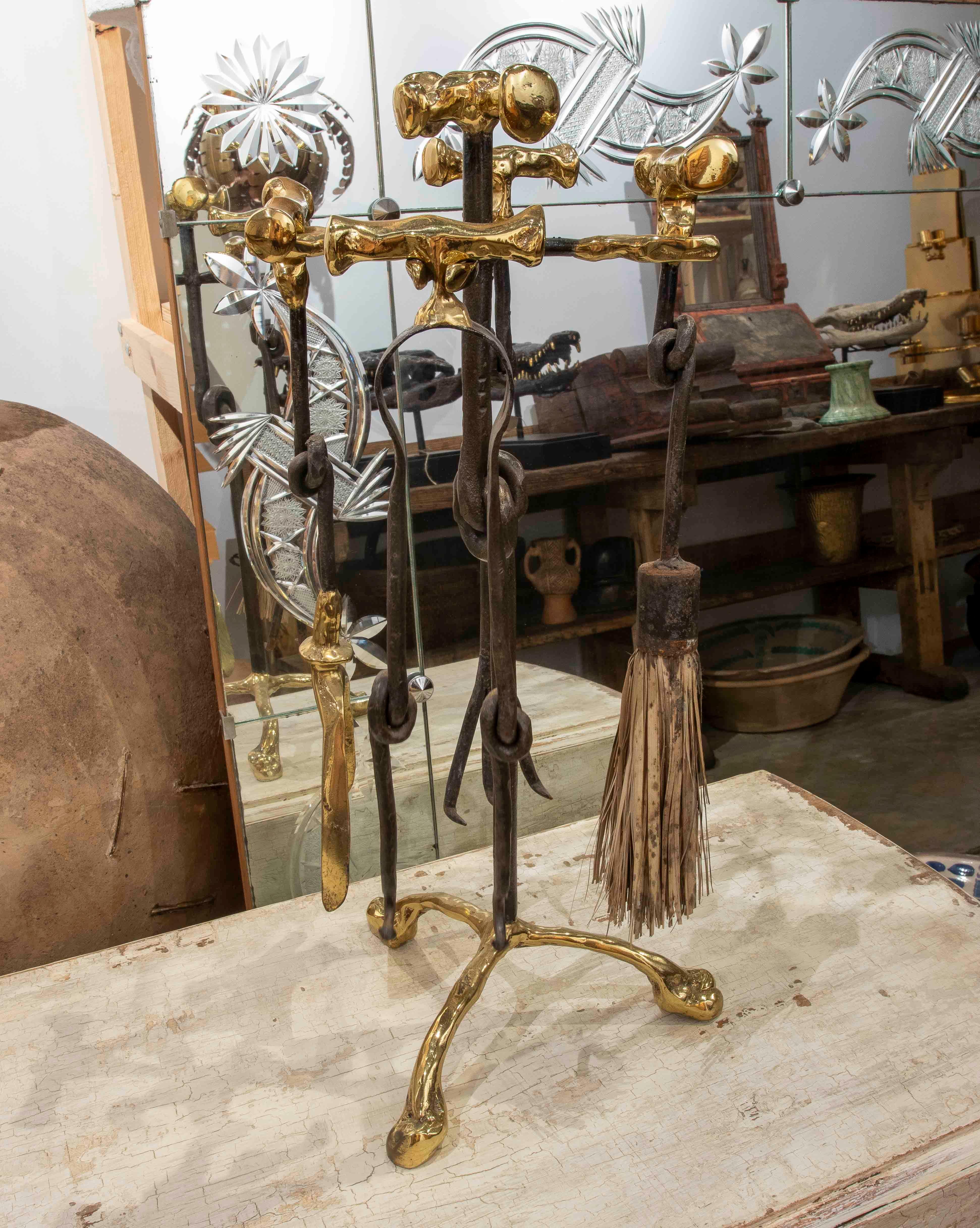 Juego de herramientas para chimenea compuesto por un cepillo, unas pinzas, un atizador y una pala, todo ello suspendido de un elegante armazón de hierro forjado con remates de latón pulido de formas orgánicas.

La combinación de materiales nobles y