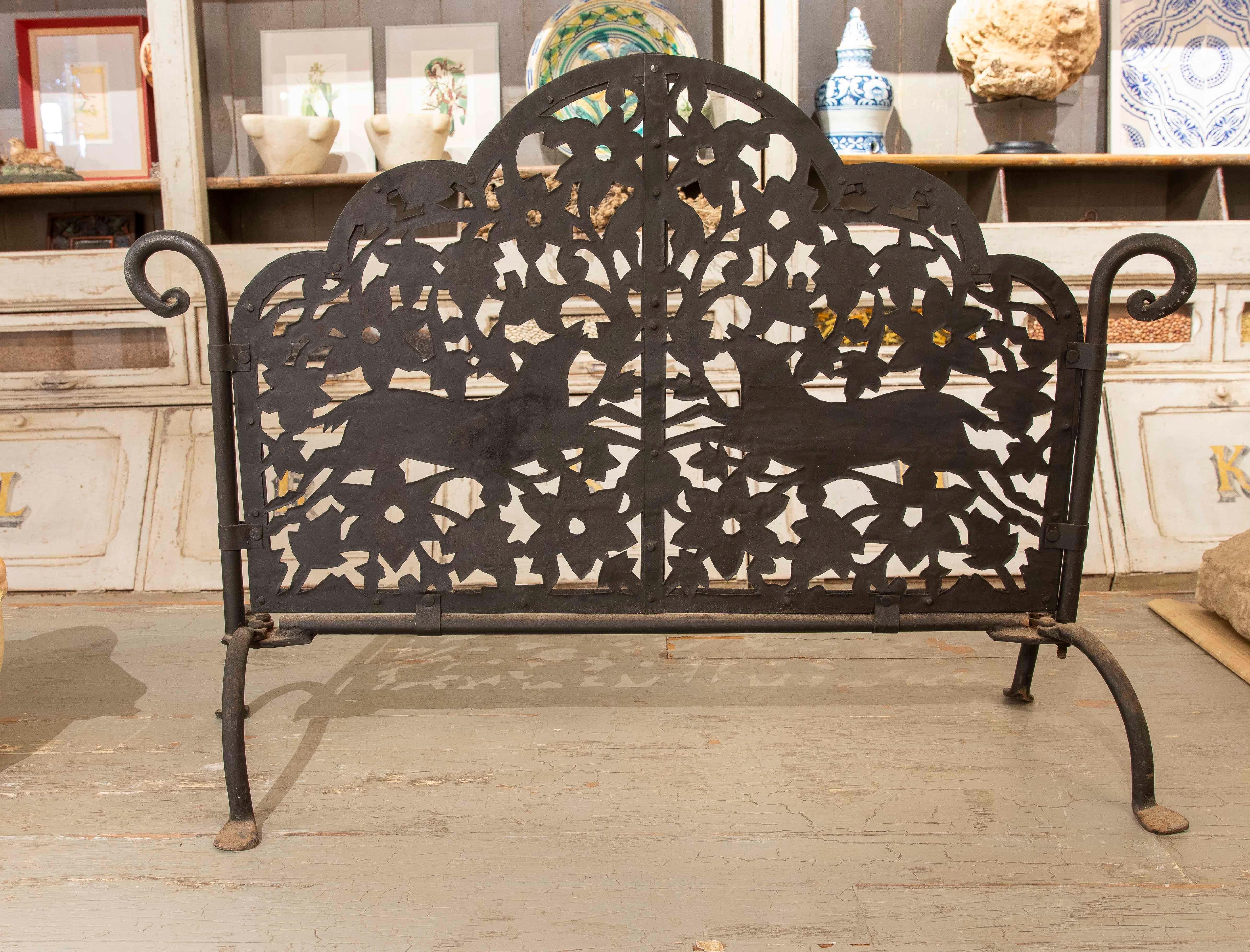 Elegante paravento per caminetto in ferro battuto con un intricato disegno con motivi floreali e la figura di un cervo stilizzato. La sua struttura ad arco e i suoi bracci curvi lo rendono funzionale e decorativo. Ideale per proteggere l'area