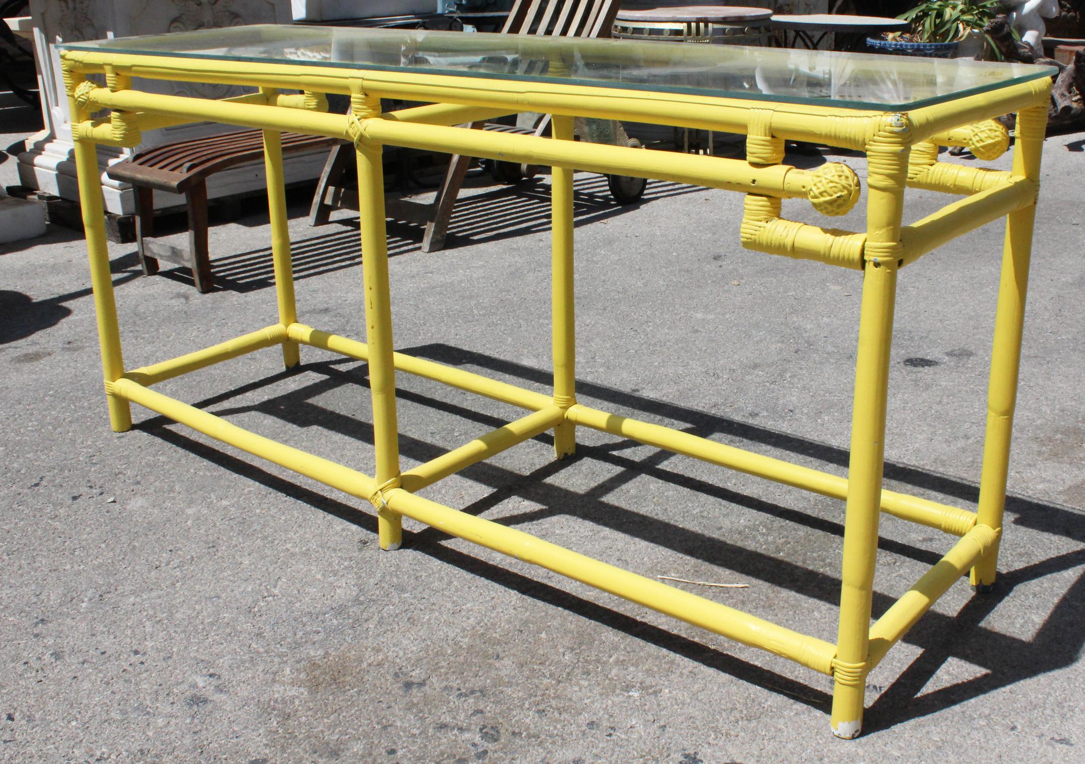 1970s yellow bamboo console table with glass top.