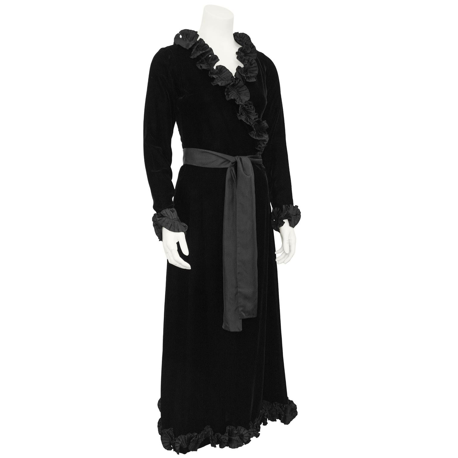 Absolutely breathtaking Yves Saint Laurent Rive Gauche wrap style maxi evening dress from the 1970s. Black velvet with a lovely silk taffeta textured, pleated ruffle trim at the neckline, cuffs and hem. Black silk belt ties at the waist that can be