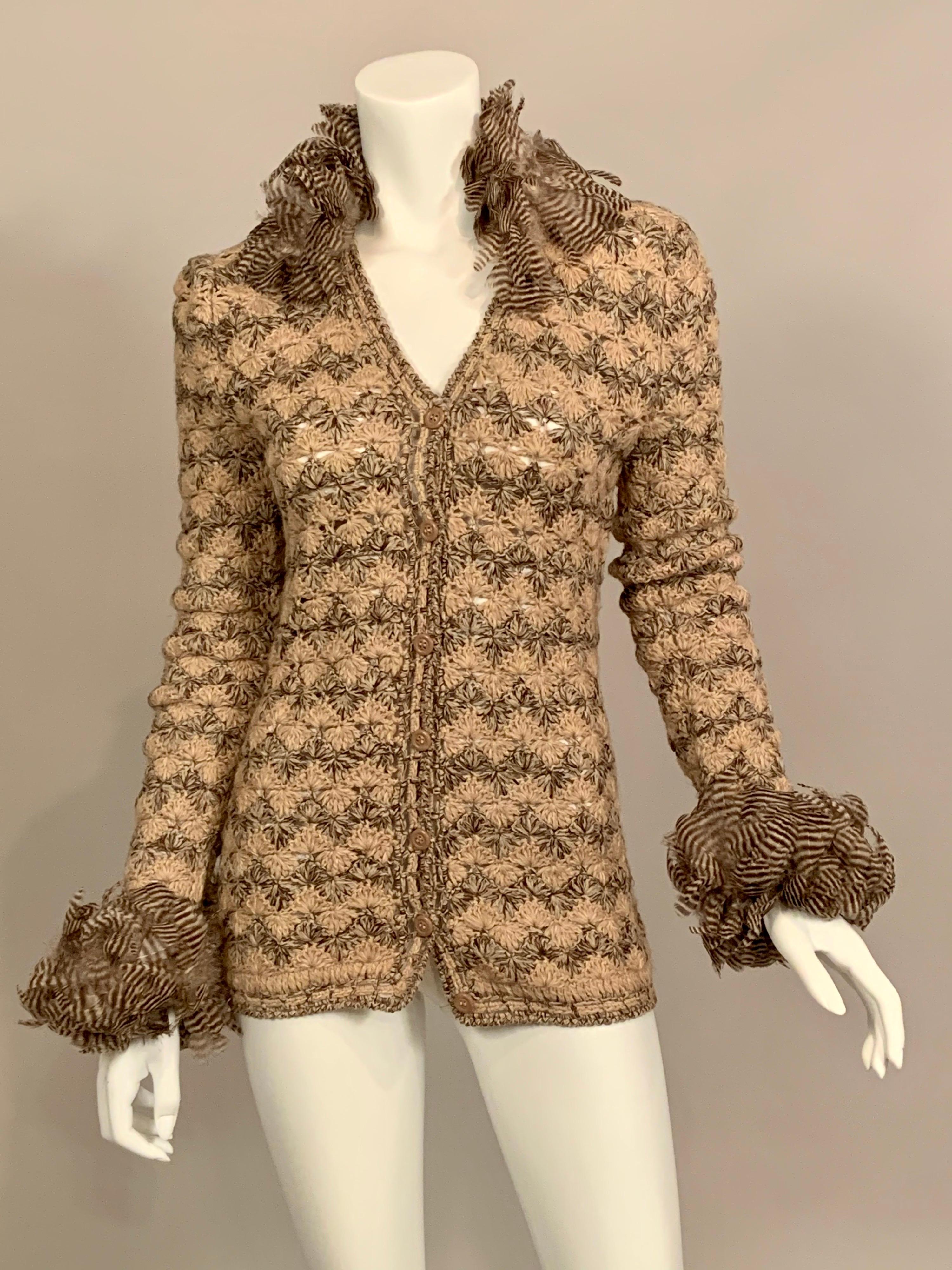 The collar and cuffs of this lightweight crocheted sweater from Yves Saint Laurent are trimmed with a wide band of brown and cream feathers which take this sweater to the next level of design.  Beige and brown lightweight yarn is used to create an