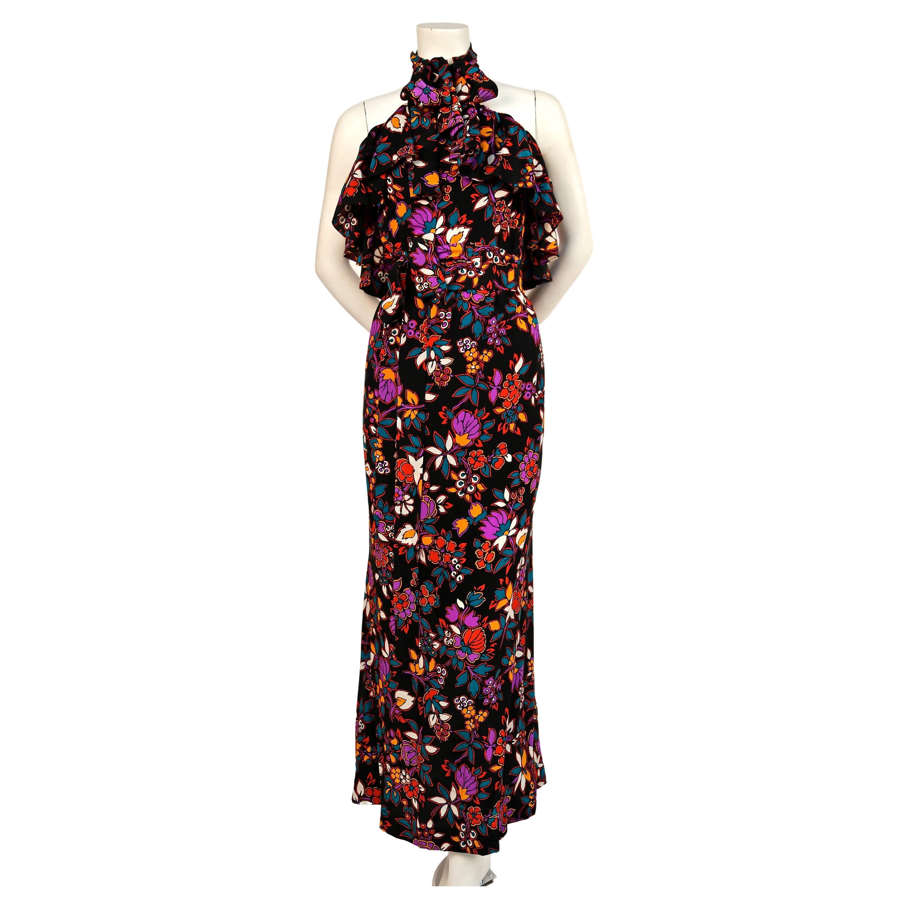 Very unusual, black floral printed silk dress with halter neck, flounce at bust and matching long sash from Yves Saint Laurent dating to the late 1970's. Halter neck can be tied at back of neck or worn with a bow in front. Labeled a French size 40