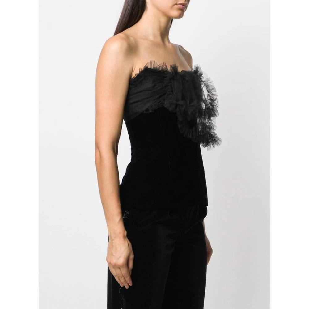 Yves Saint Laurent black velvet top. Sweetheart neckline with decorative tulle ruffles. Strapless and zip closure and front hook.
Years: 70s

Made in France

Size: 40 IT

Flat measurements

Height: 45 cm
Bust: 37 cm