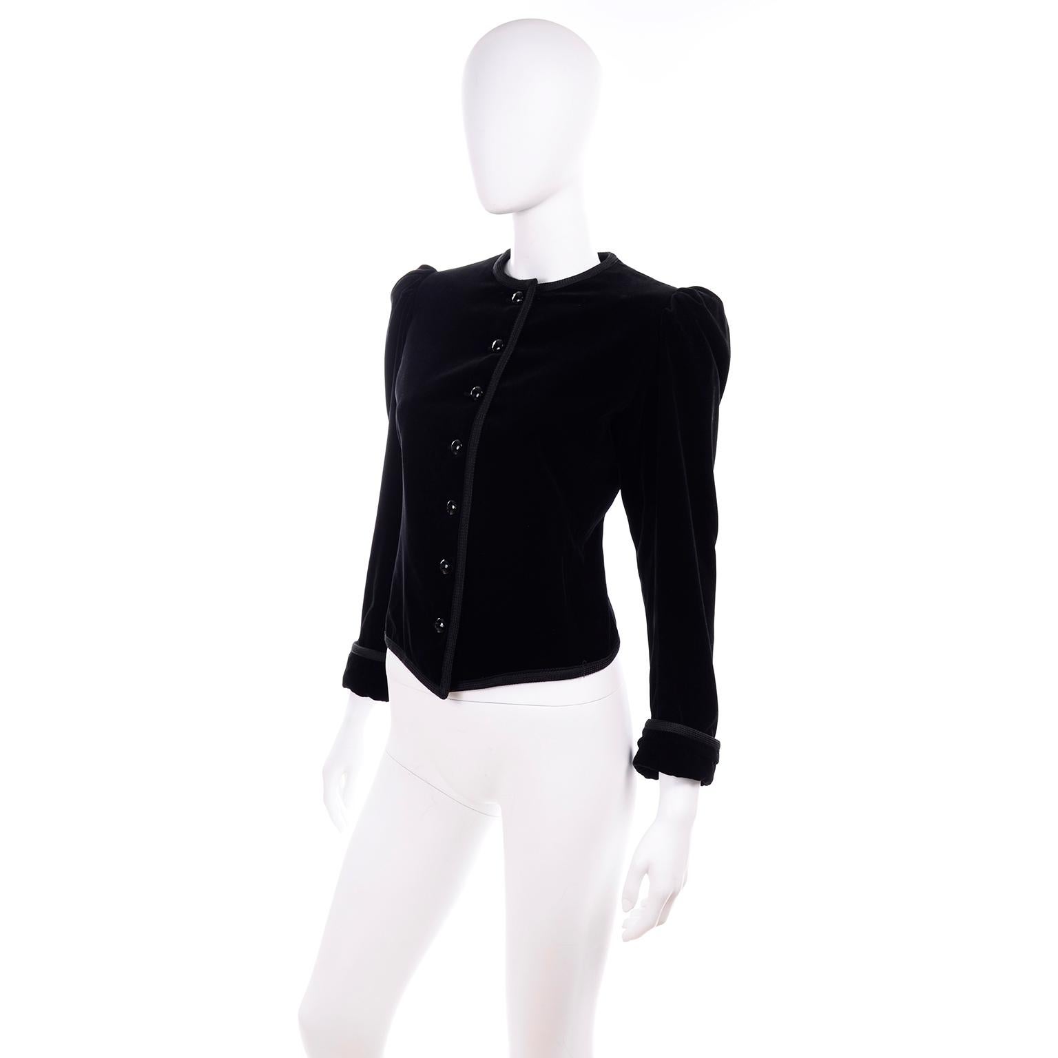 This is a timeless vintage black velvet jacket designed by Yves Saint Laurent in the late 1970's. There are gentle shoulder pads and pleated shoulders to create puff sleeves and the jacket has Saint Laurent's signature braided trim, round buttons,