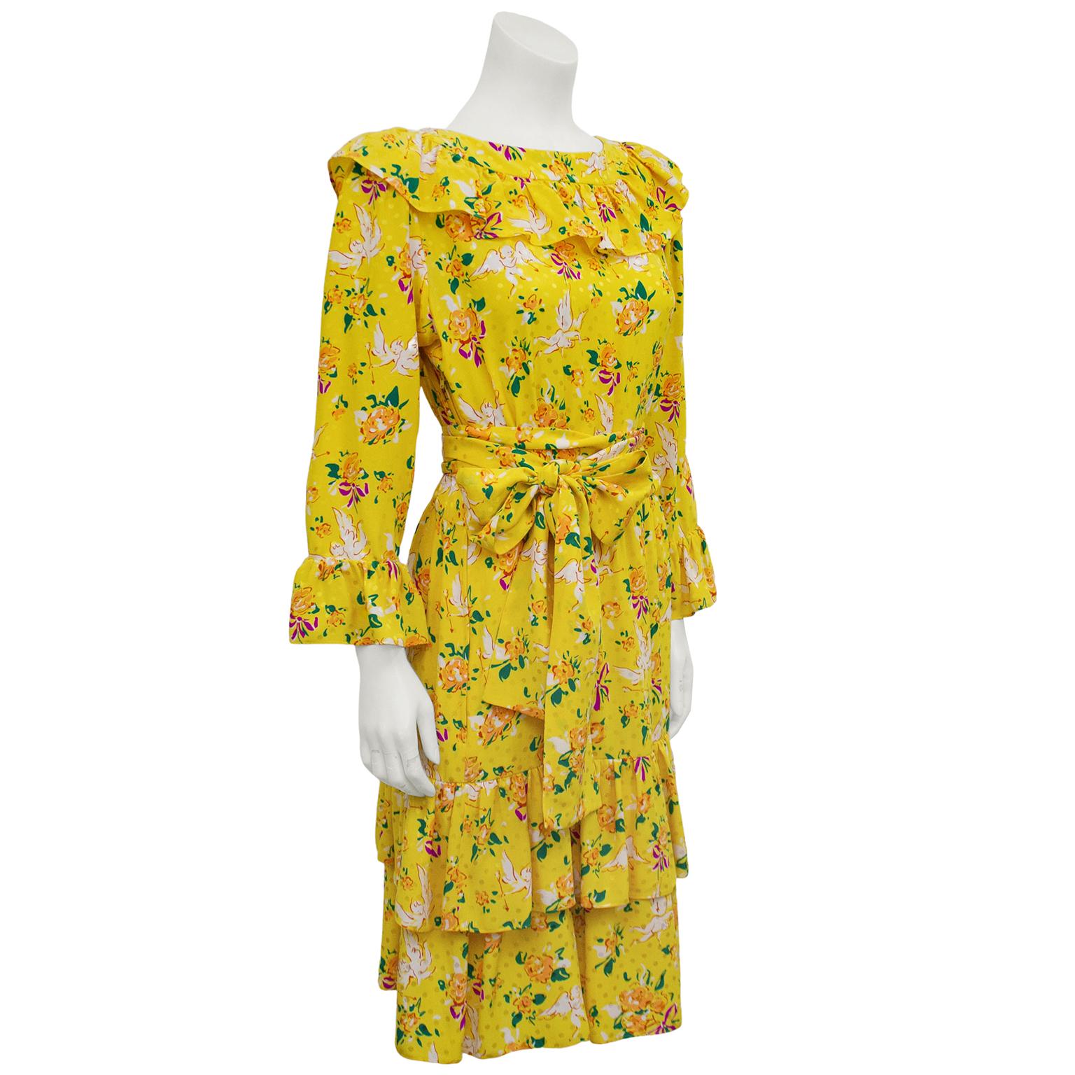 Early Yves Saint Laurent bright yellow, long sleeve, silk jacquard dress from the 1970s. Monochromatic yellow silk with yellow polka dots allover. Print includes cute white cupids, orange, green and red flowers with purple bows. Large ruffle at