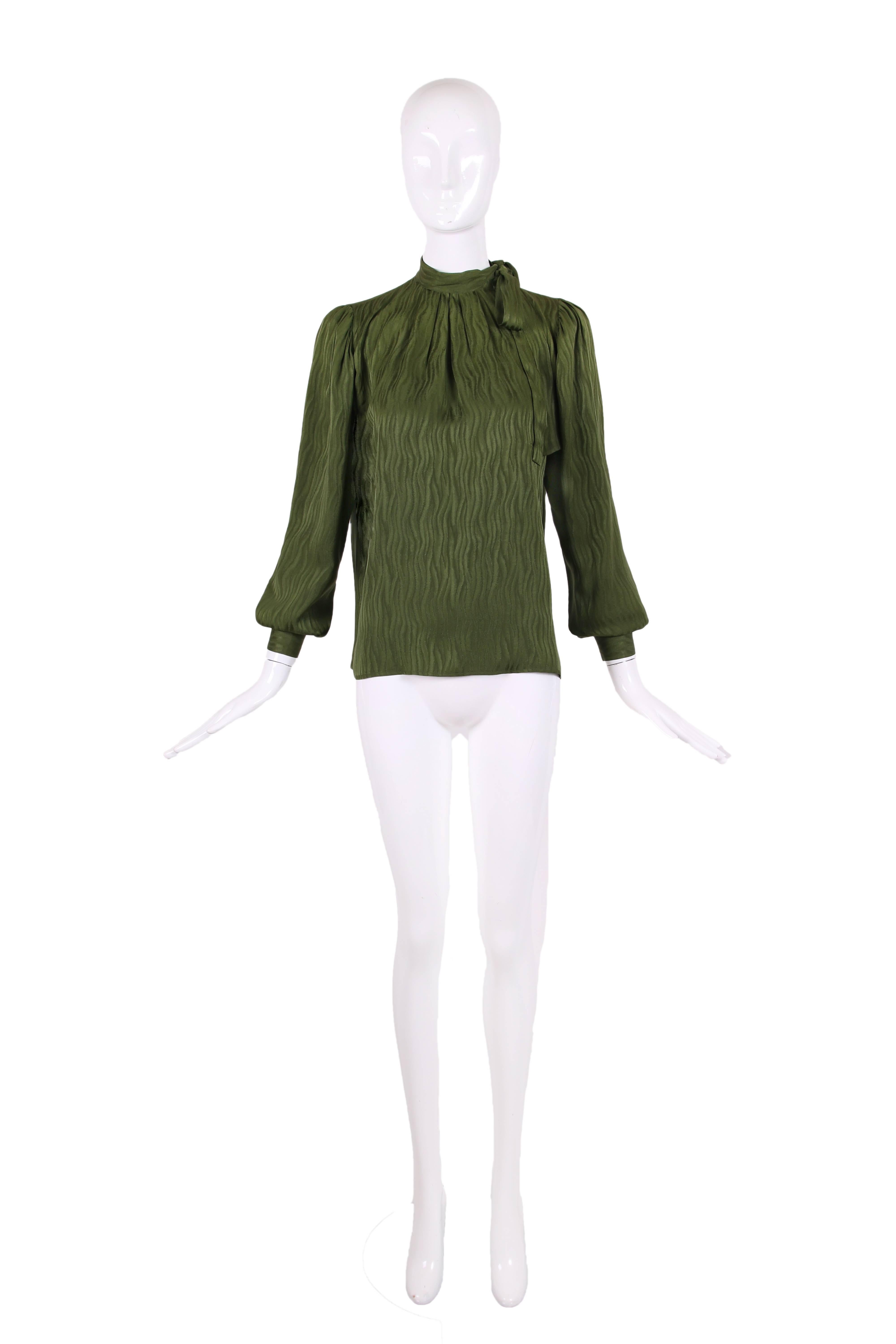 1970's Yves Saint Laurent 100% silk green long sleeved blouse with a placket left of center front with five button closures and side neck ties. This blouse features a wave pattern all over. In excellent condition with a few pin point sized marks on