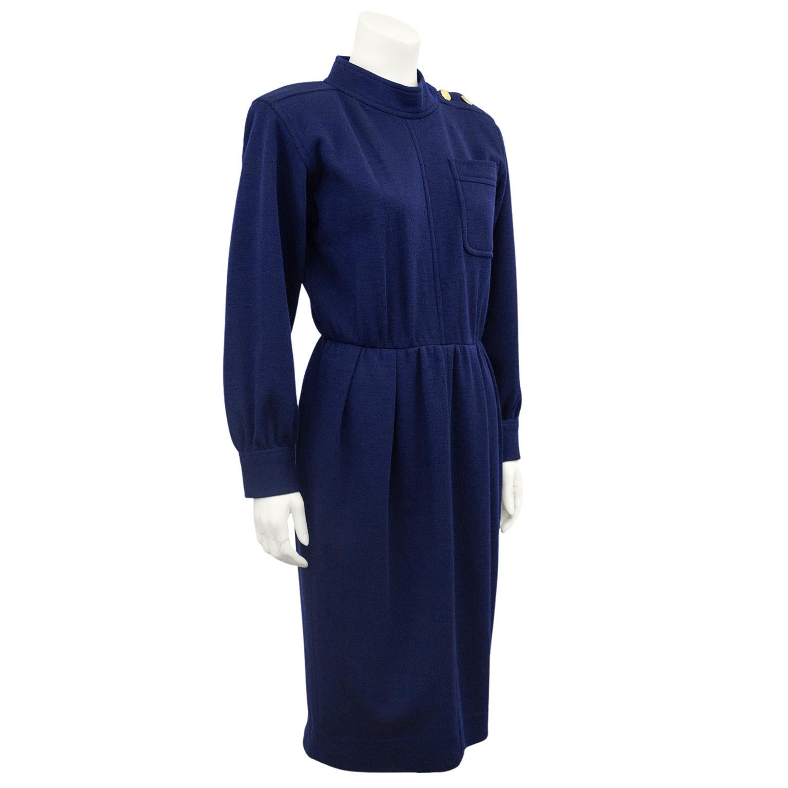 1970s Yves Saint Laurent Rive Gauche navy blue wool day dress. Mock turtleneck collar, long sleeves with small gather at cuff and single patch left breast pocket. Three large gold tone buttons on left shoulder. Fitted at waist and straight skirt