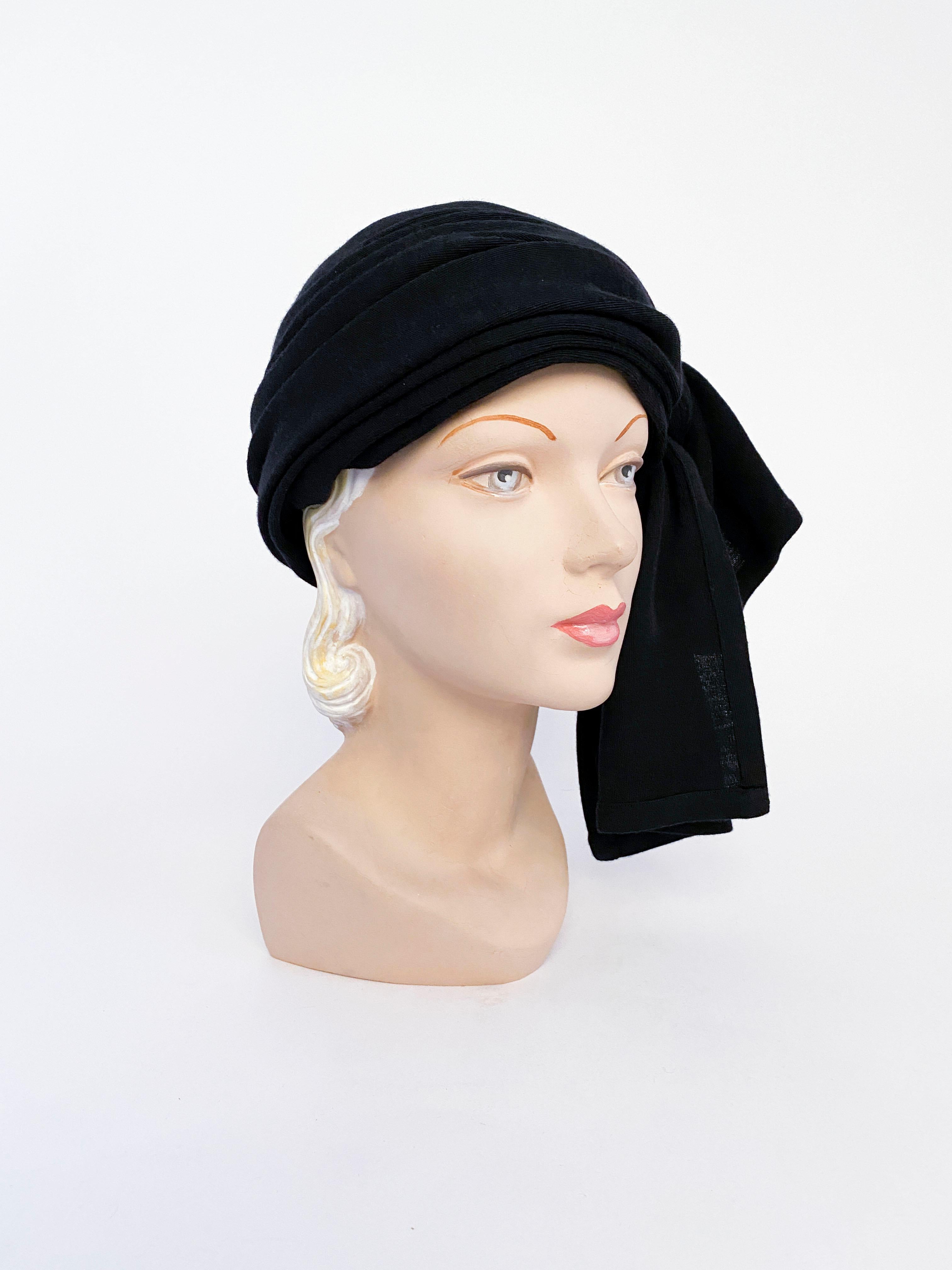 1970s Yves Saint Laurent black knit turban with a fully gathered body, tying on the side to create a decorative knot and double hanging drapes.