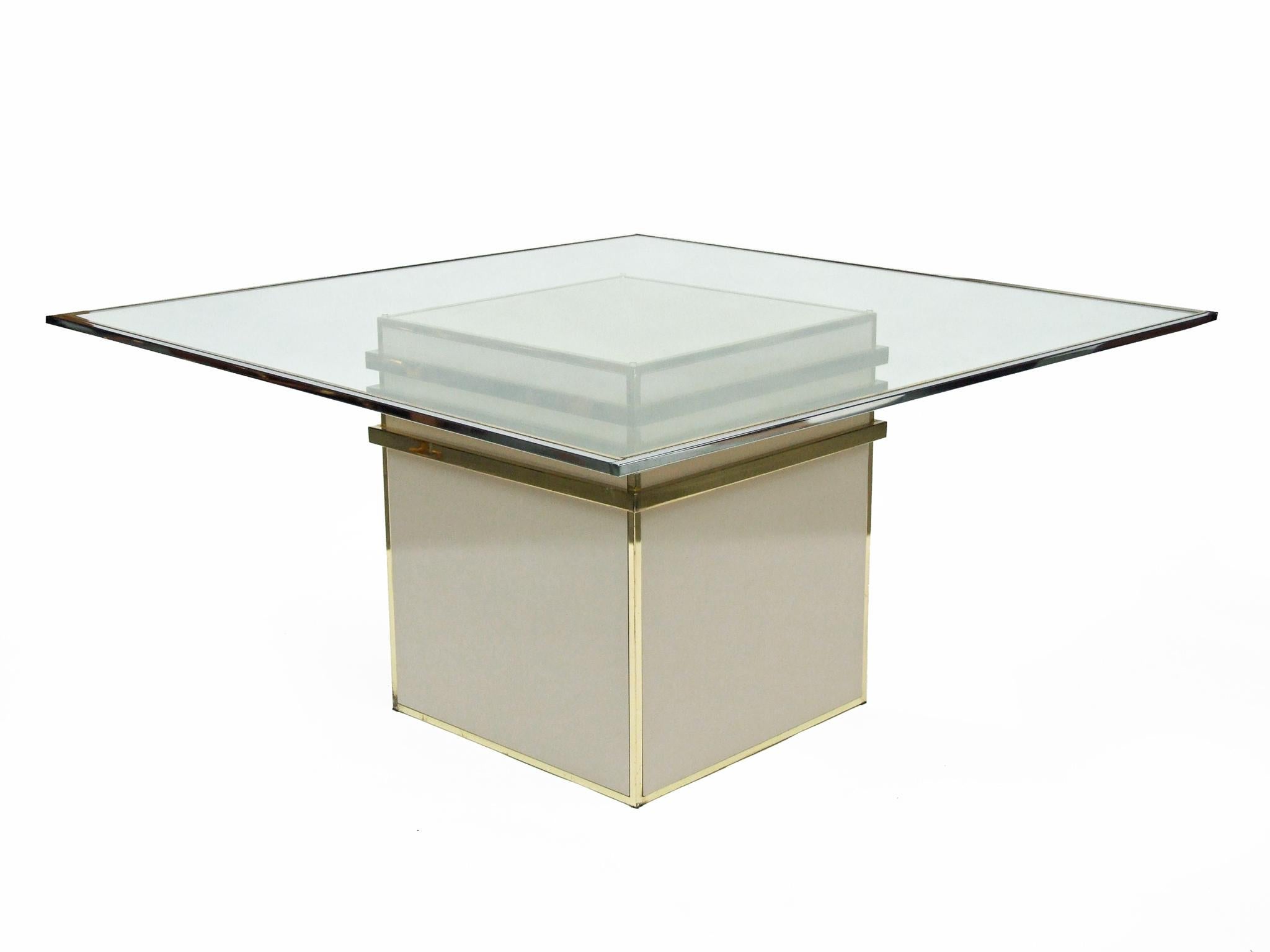 1970s reception dining table designed by Renato Zevi, Italy.
Cream laminate base with a brass plate design.
Large square clear glass top with a chrome and brass plate metal frame.

The table does have light pitting to the metal, but this is