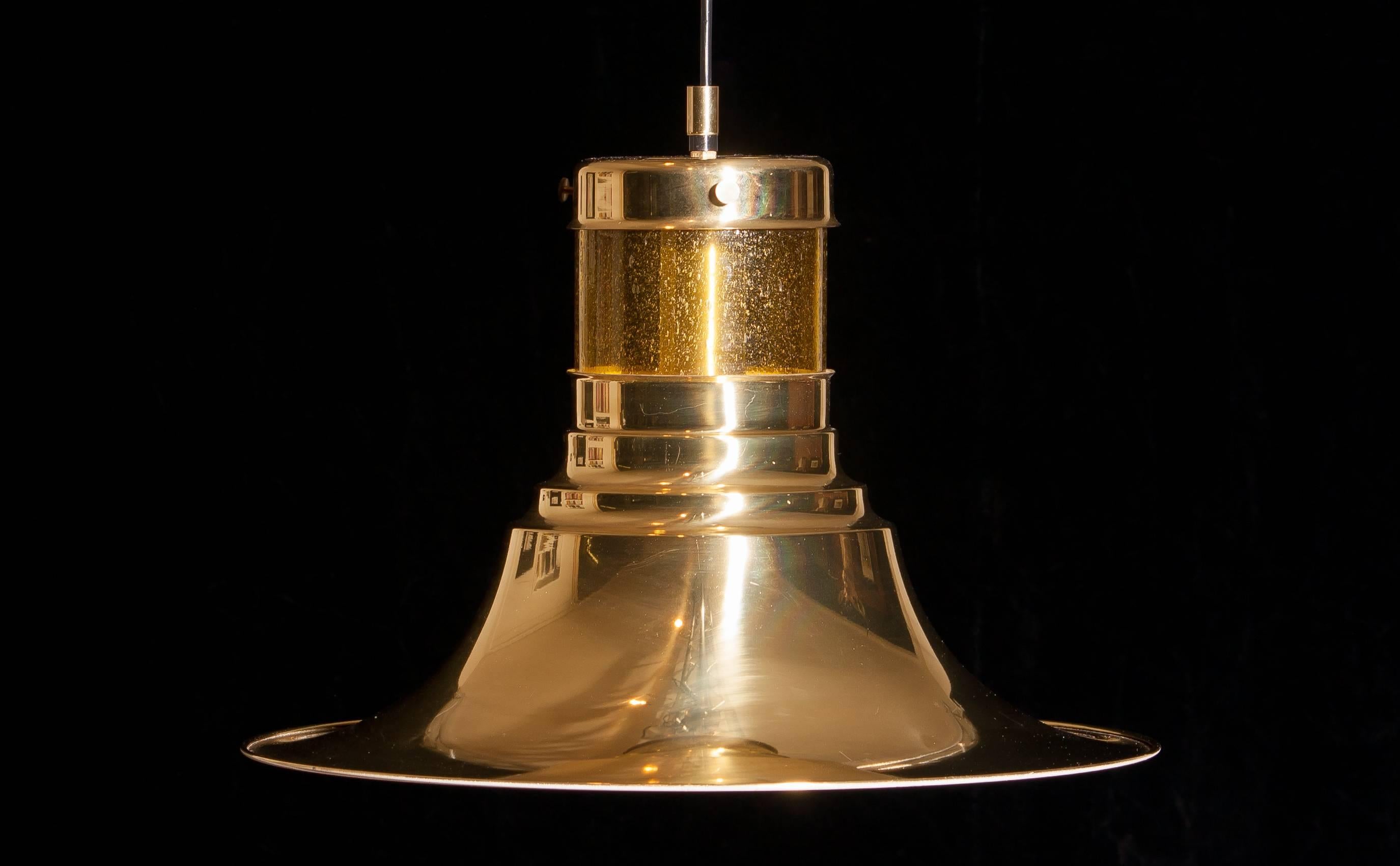 Magnificent pendant designed by Börje Claes for Norellet, Sweden.
This lamp is made of brass with an enamel white inside and a yellow cylinder of glass.
The beautiful shape makes that it gives a wonderful shining.
Period 1970s.
Dimensions: H 32