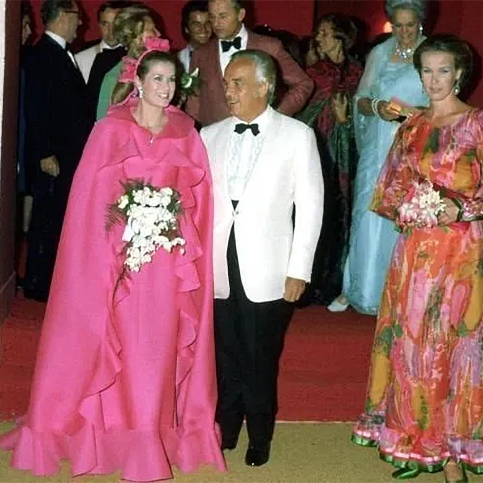 Marc Bohan a créé cette superbe robe de soirée rose Christian Dior pour la collection couture Dior automne/hiver 1971. Nous la présentons sur le podium ainsi qu'une version de la robe avec une écharpe assortie portée par Grace Kelly. La couleur est