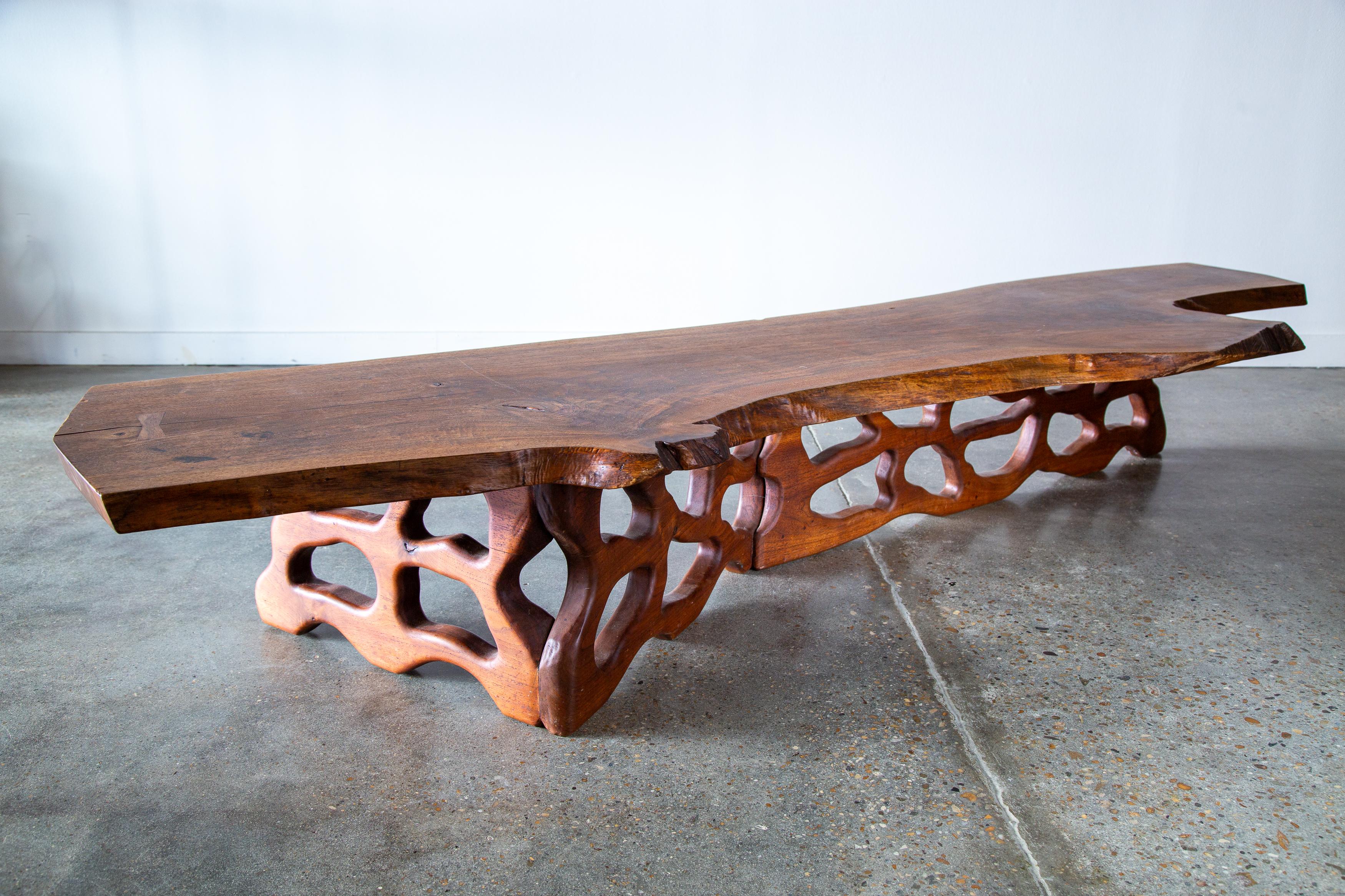 An almost 8’ long monumental live edge American Black walnut table designed and created by Gino Russo in 1972. The live edge table is elevated by an organic hand carved form that emulates a coral reef.  Rosewood butterfly keys stabilize natural